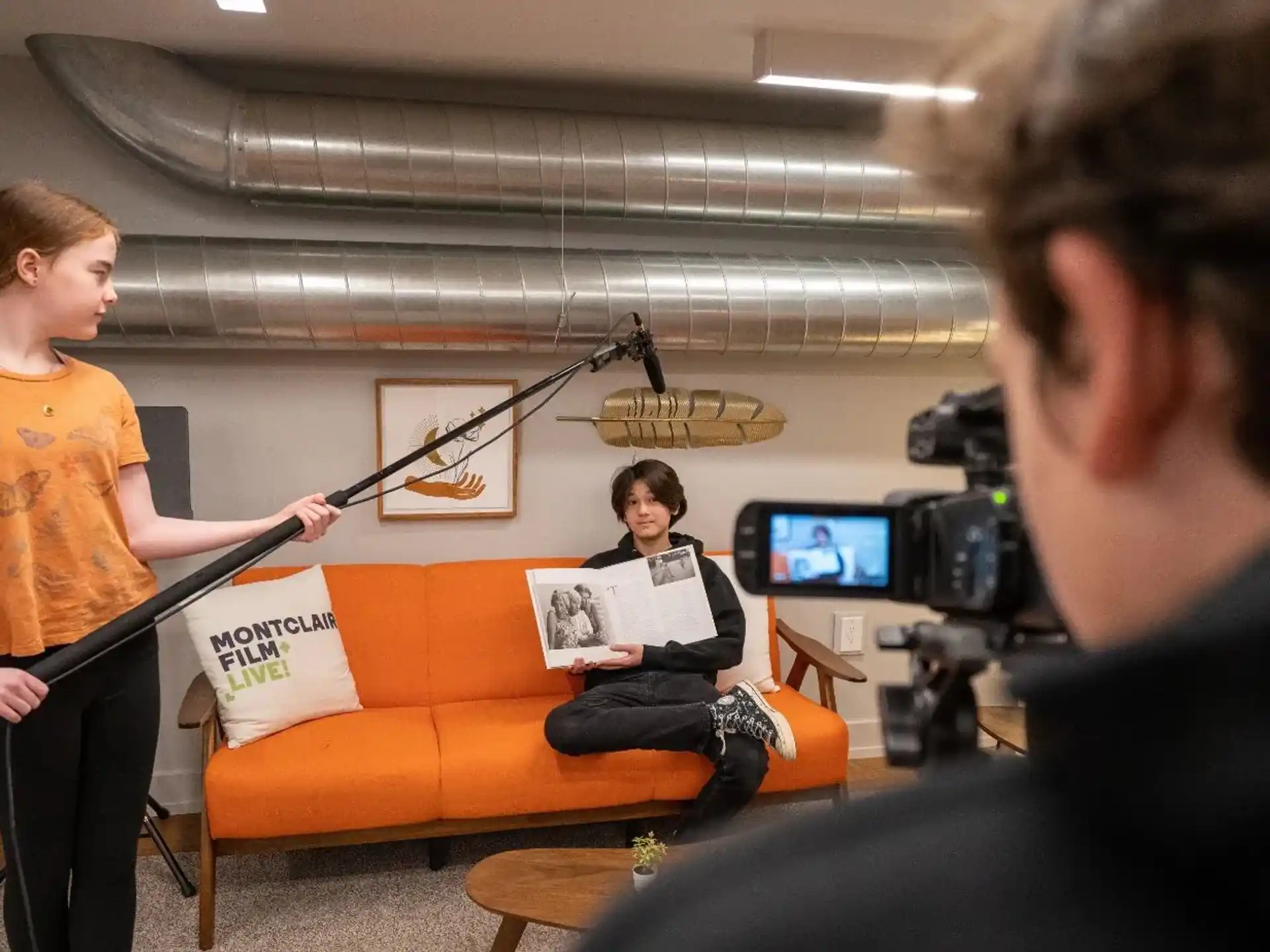 a man playing a guitar in front of a man sitting on a couch