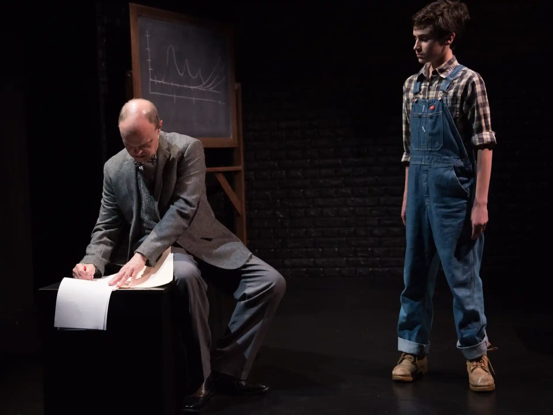 a man sitting on a chair next to a man standing