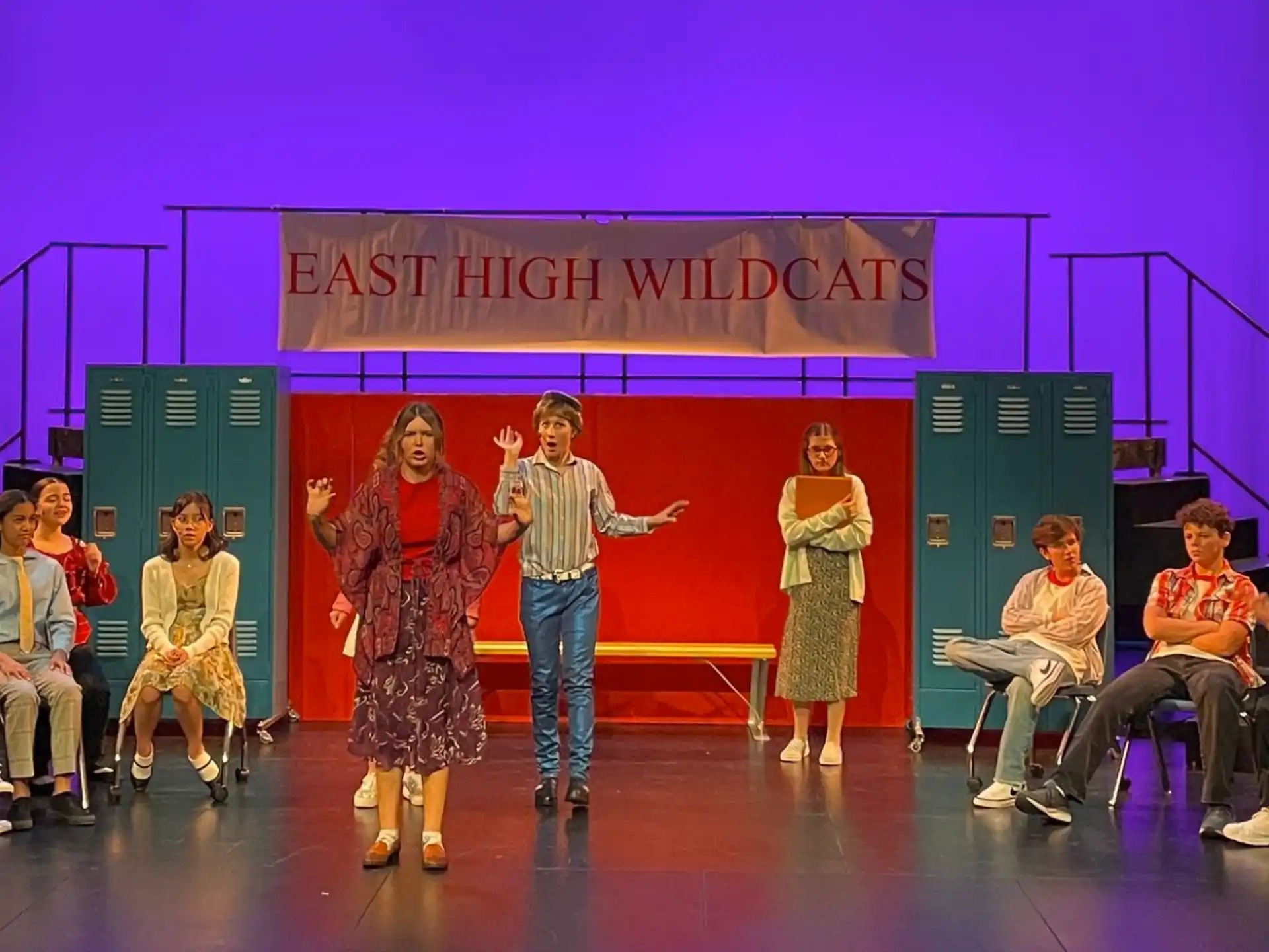 a man and woman on stage with a group of people sitting in chairs