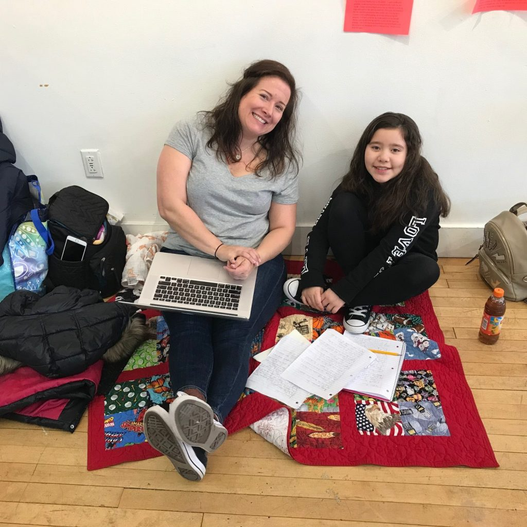 a couple of women sitting on the floor with a laptop