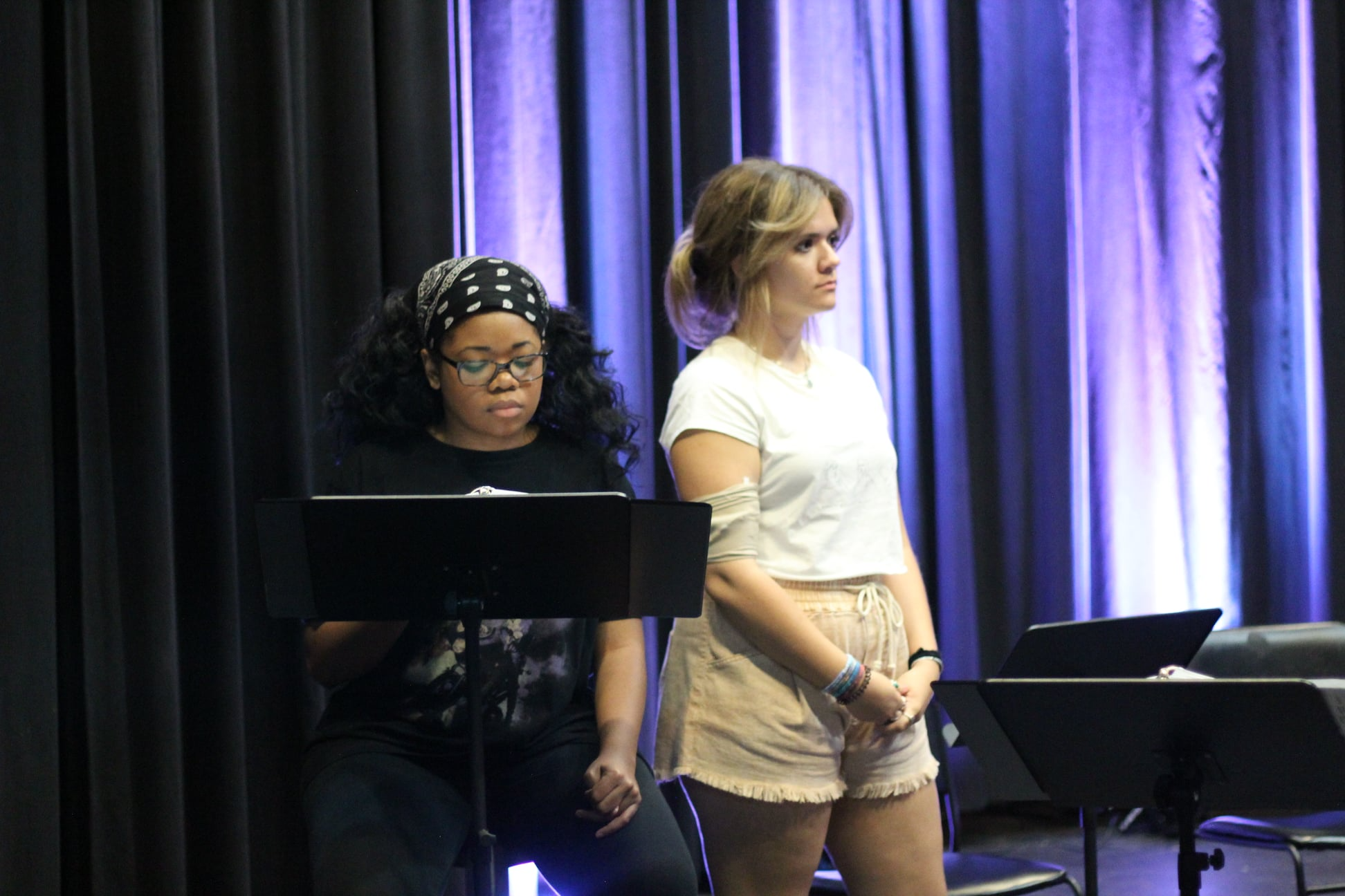 a woman standing next to a woman sitting on a chair