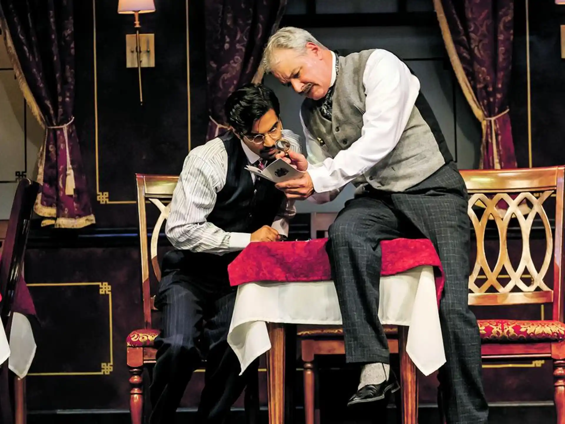 a man and a woman sitting on a chair looking at a book