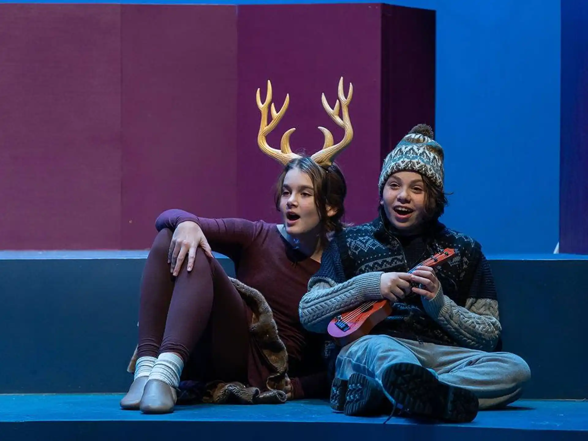 a man and a woman sitting on a stage with a crown