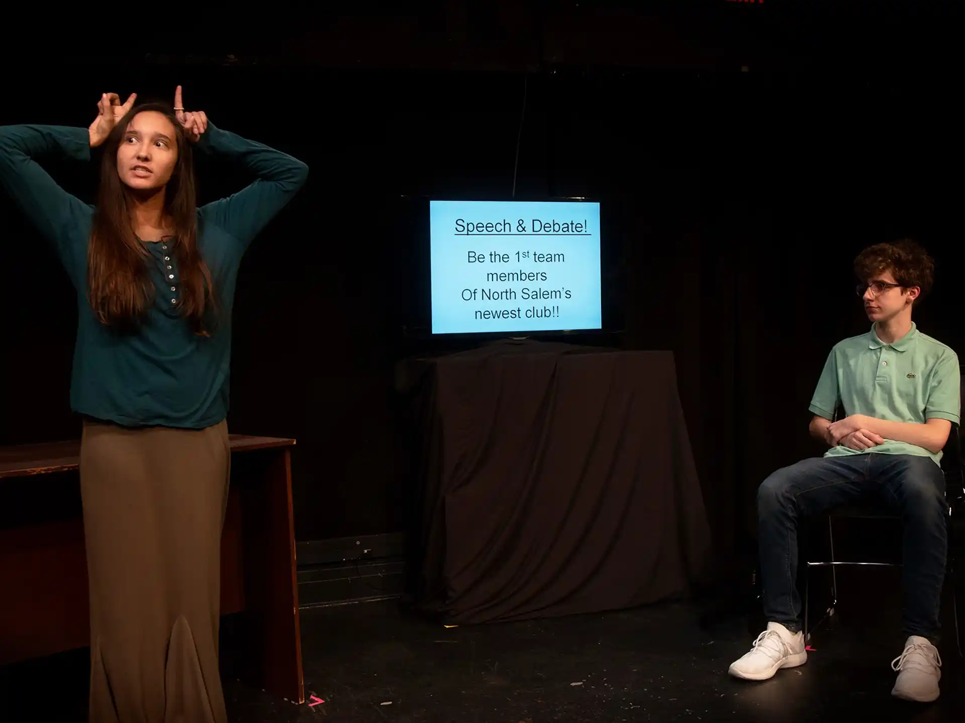 a woman standing next to a man sitting on a chair