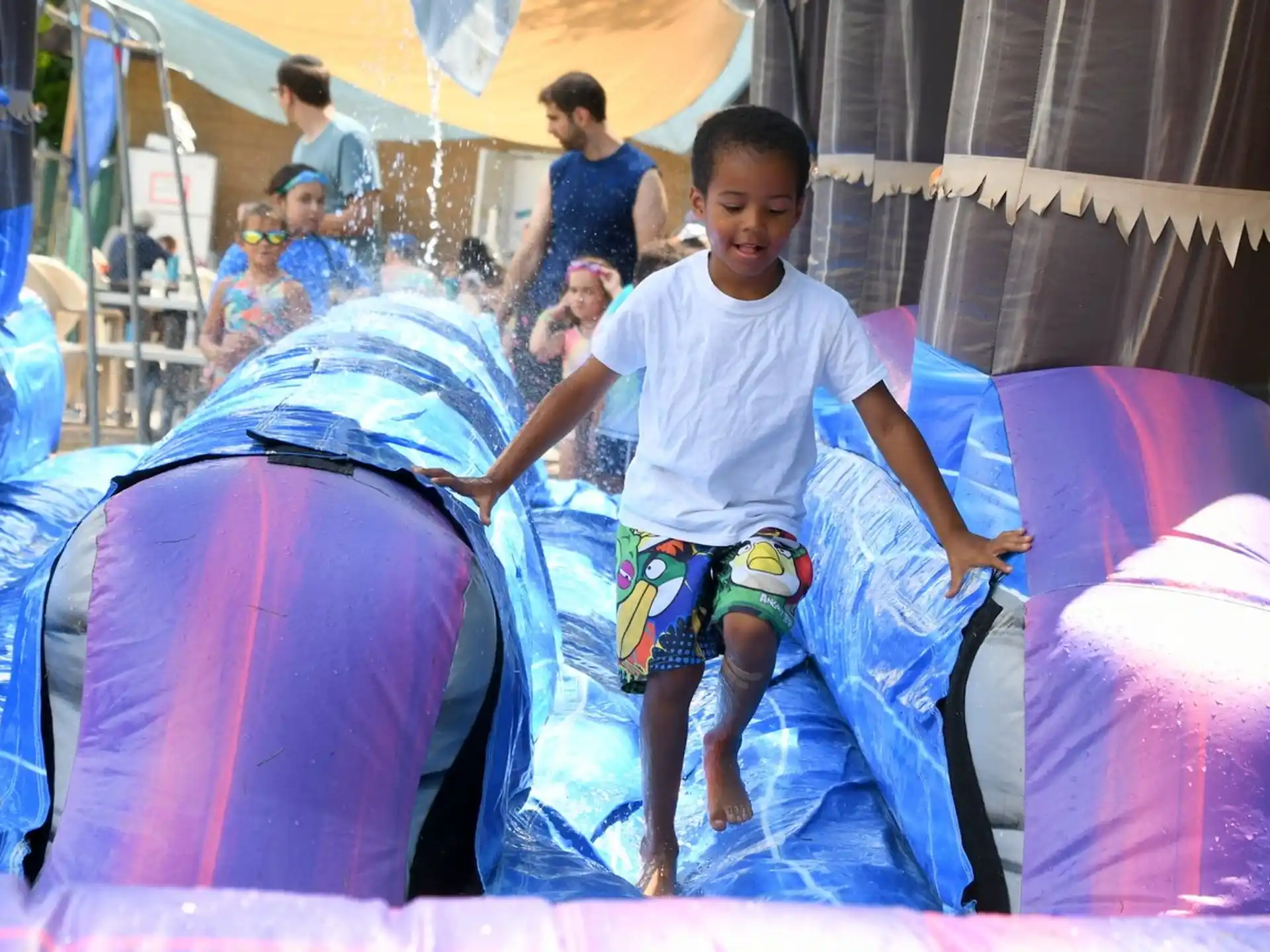 a boy standing on a large blue and pink tent