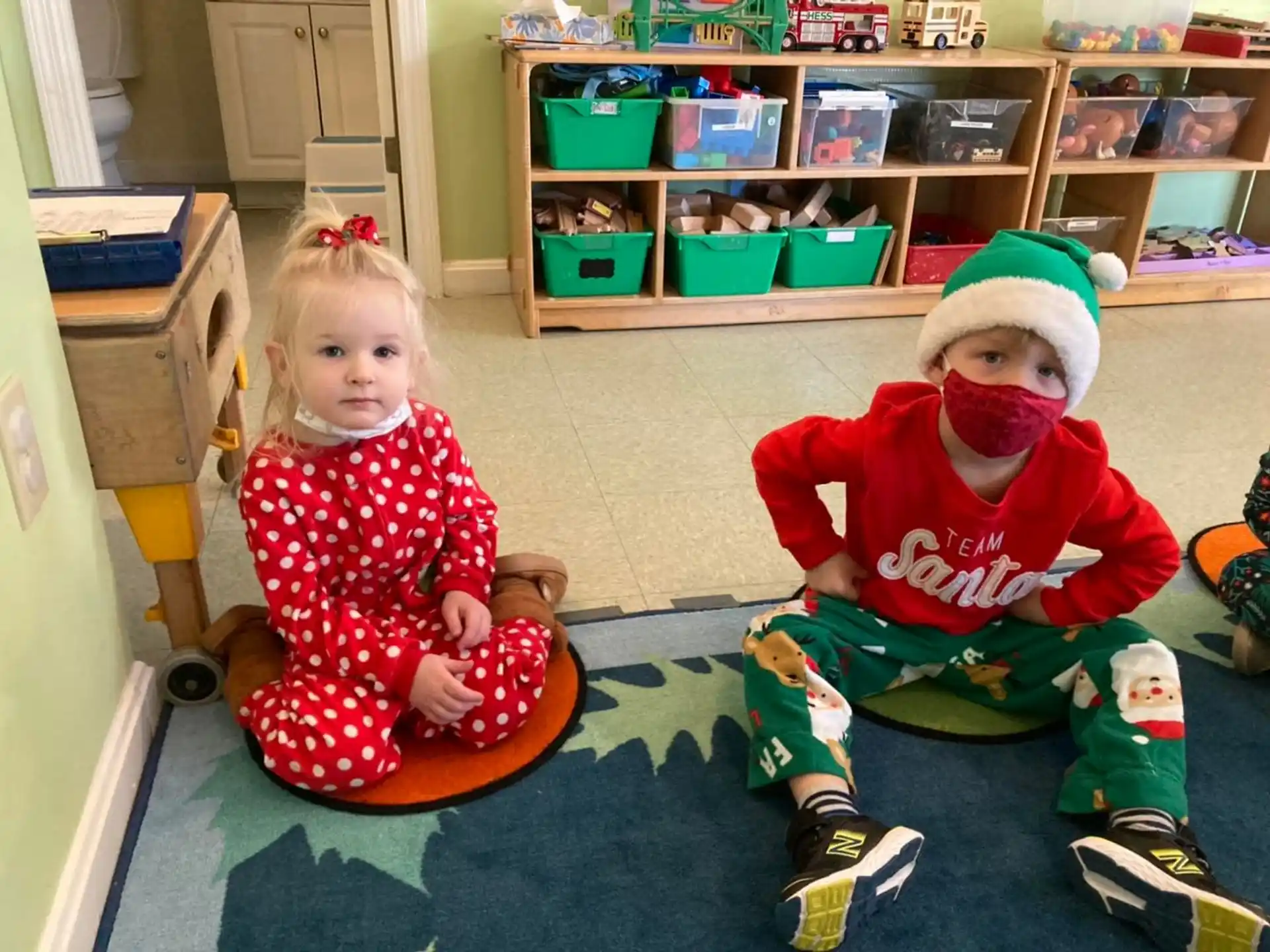 a girl and a boy sitting on a toy in a room with shelves