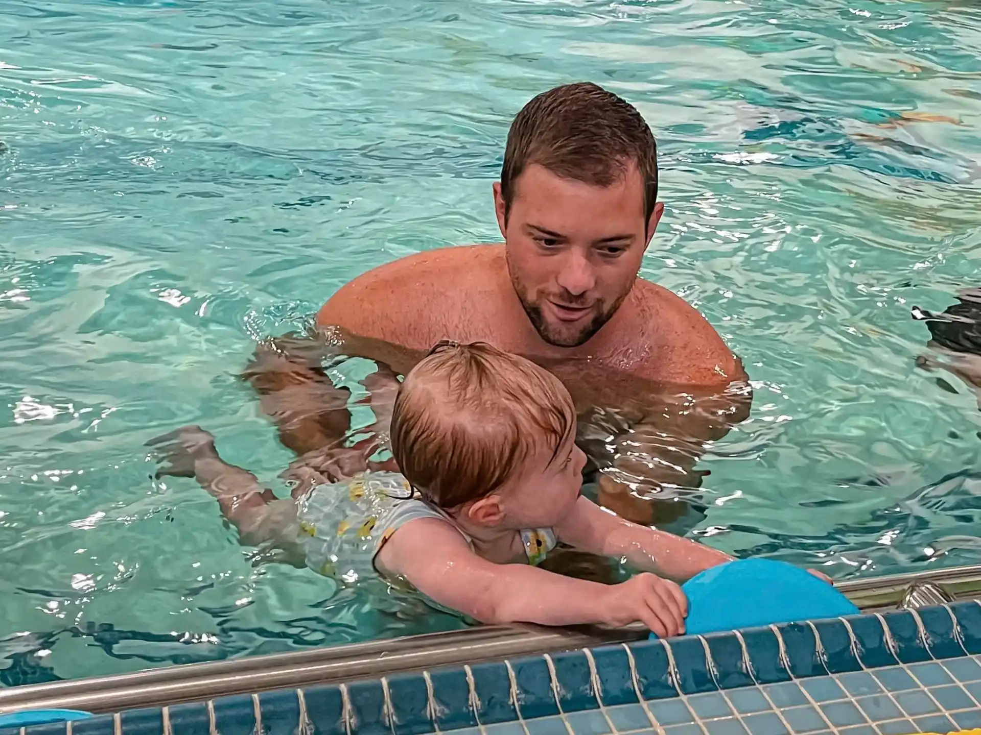 a man holding a baby in a pool