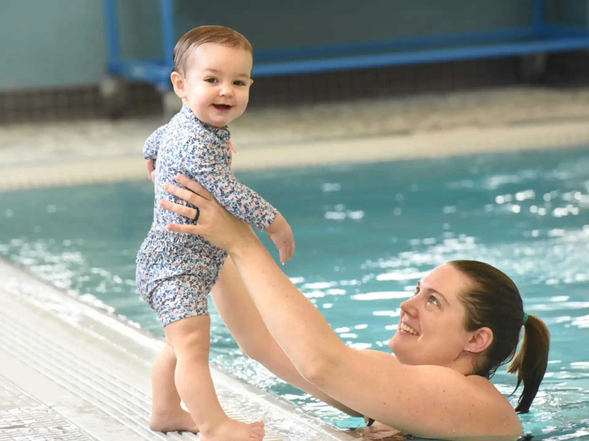a person holding a baby by a pool
