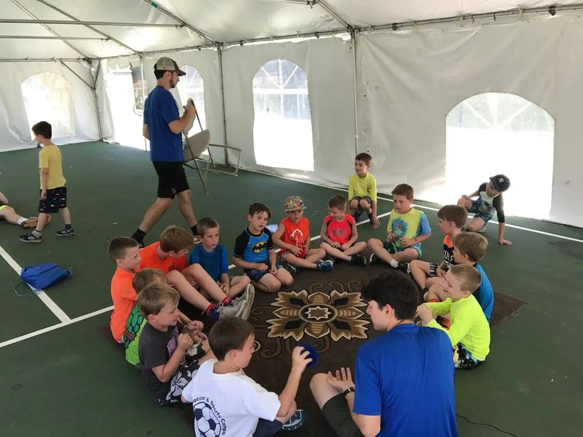 a group of children sitting on the floor in front of a man standing