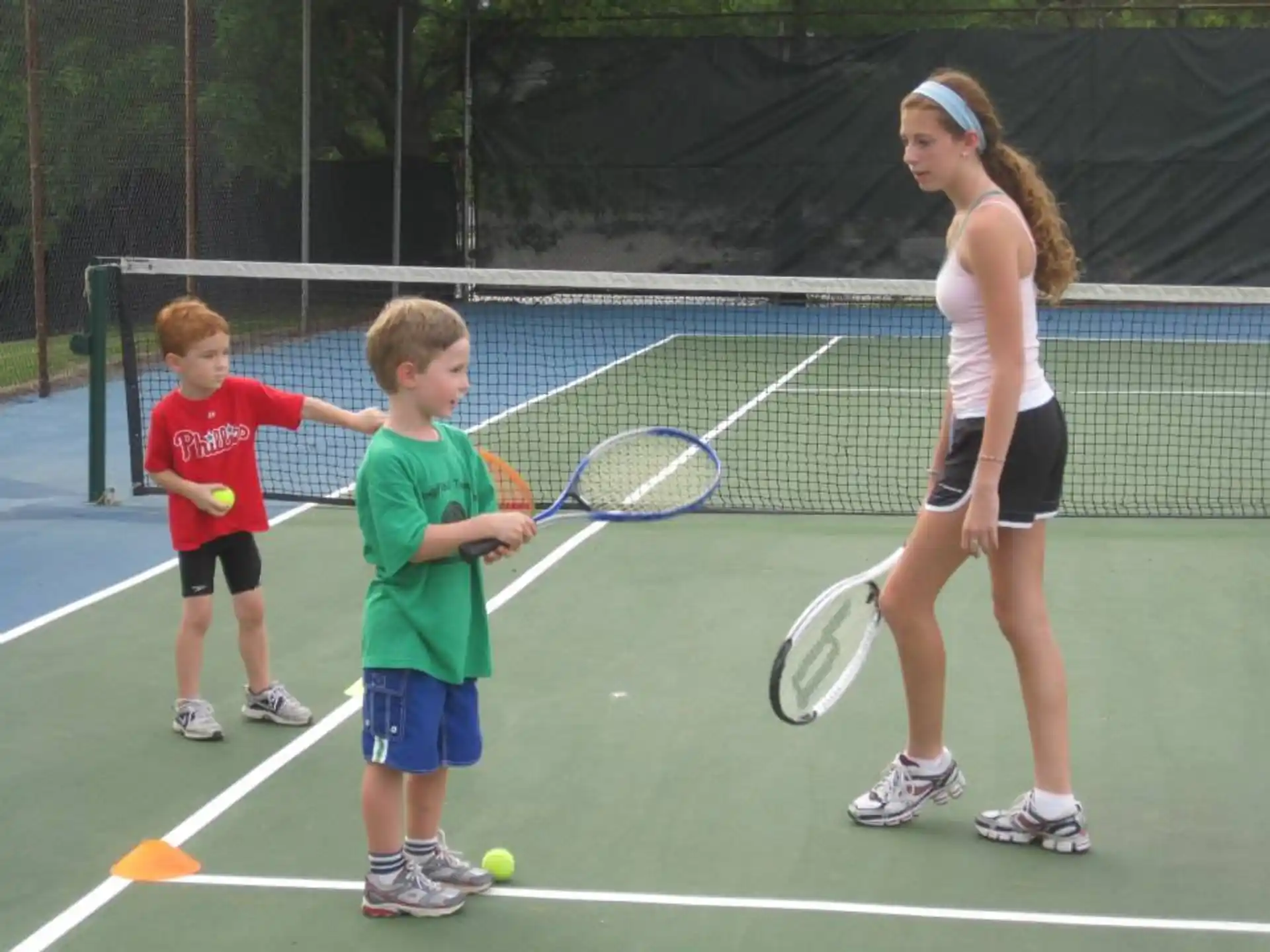 a person and kids playing tennis