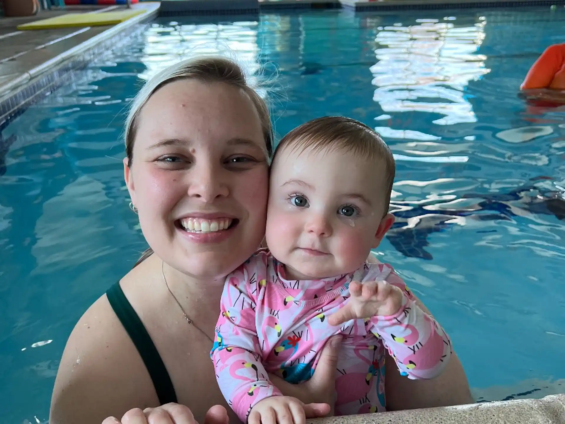 a person holding a baby in a pool