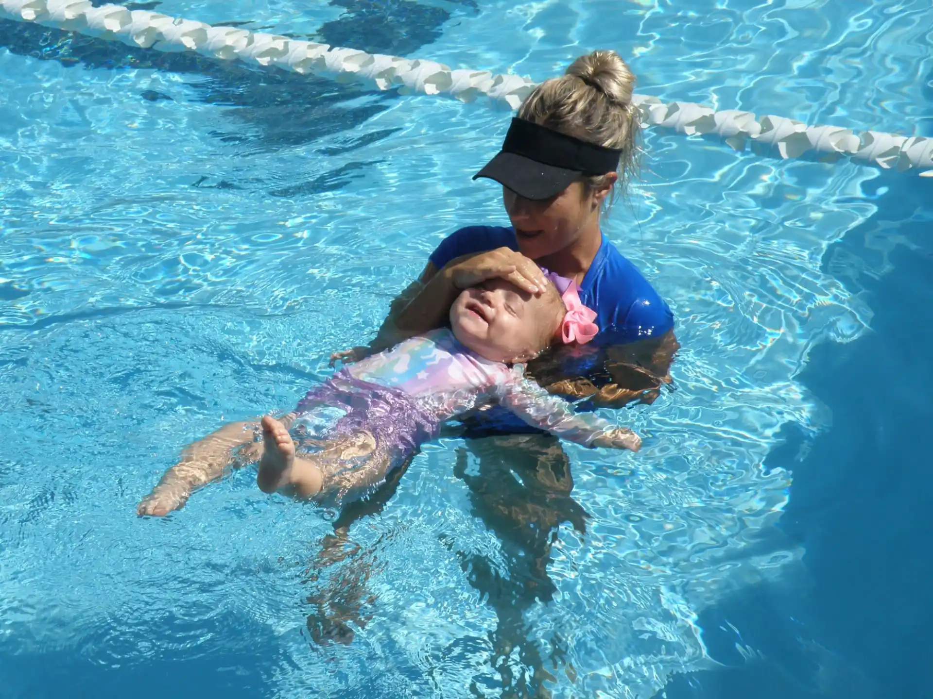 a person holding a baby in a pool