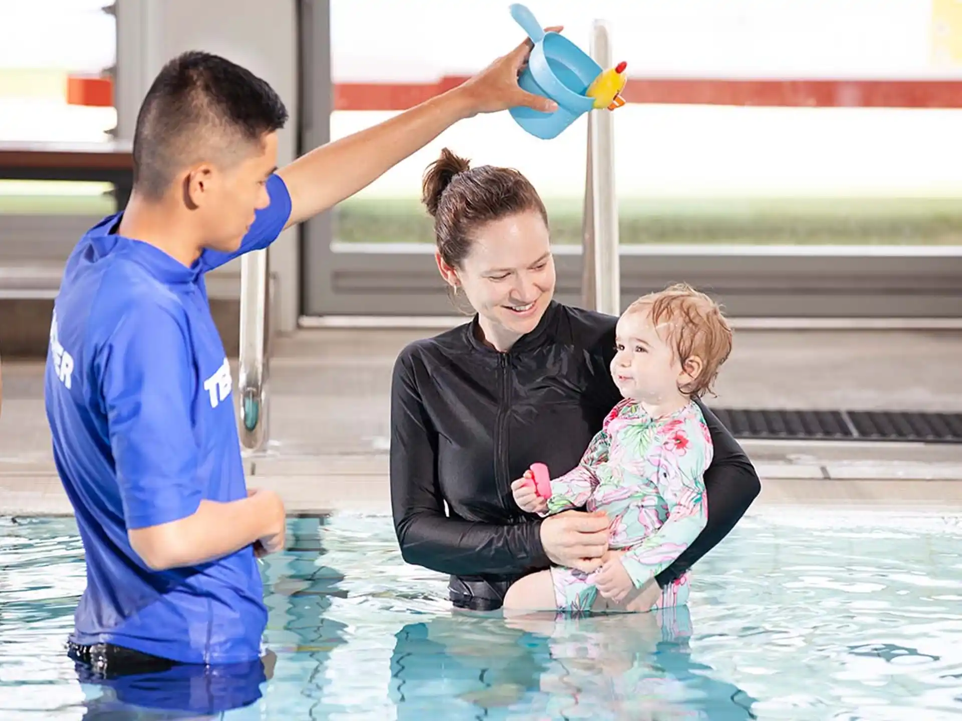 a man and a woman playing with a baby in a pool