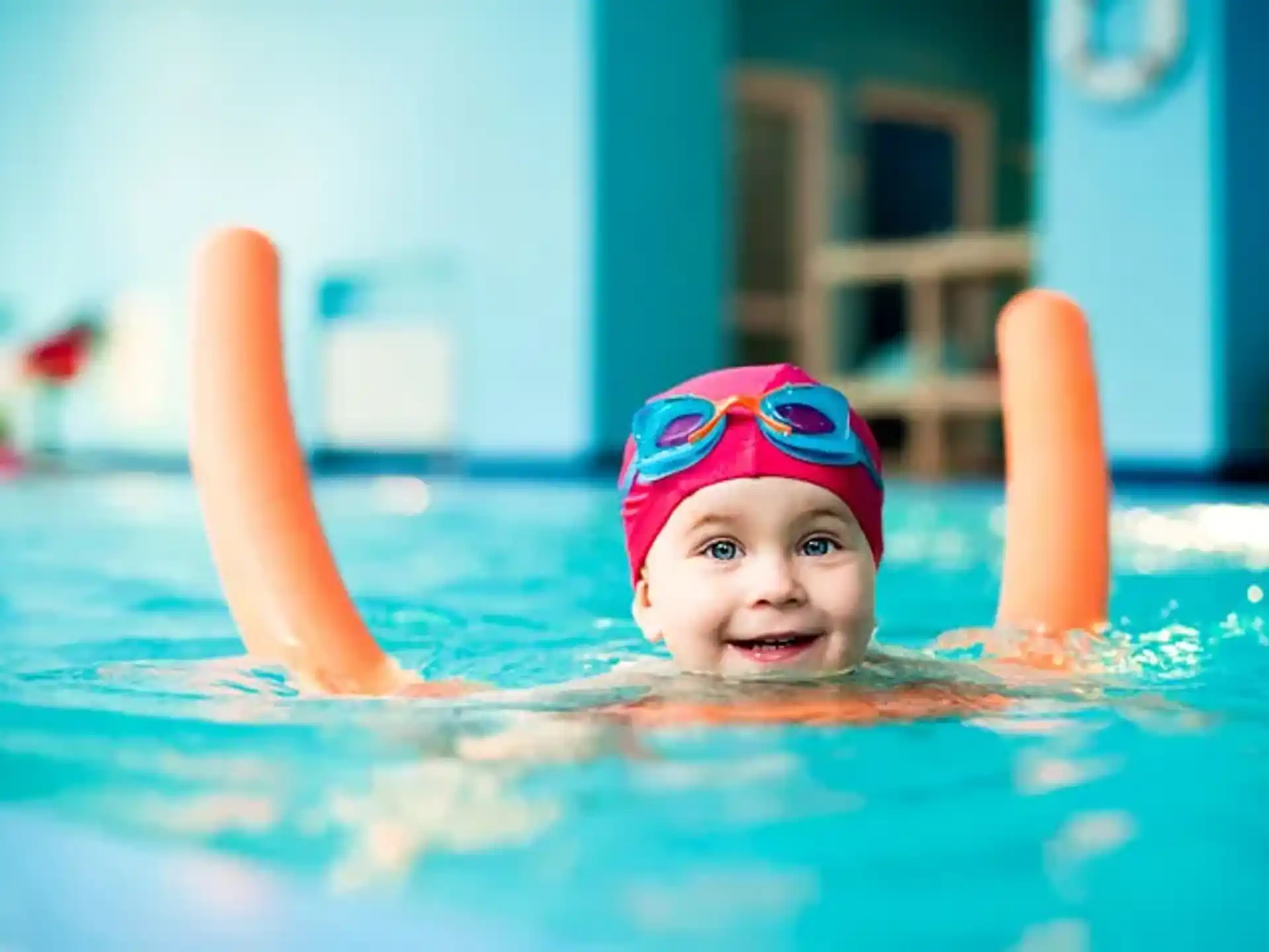a child in a pool with a toy in his mouth