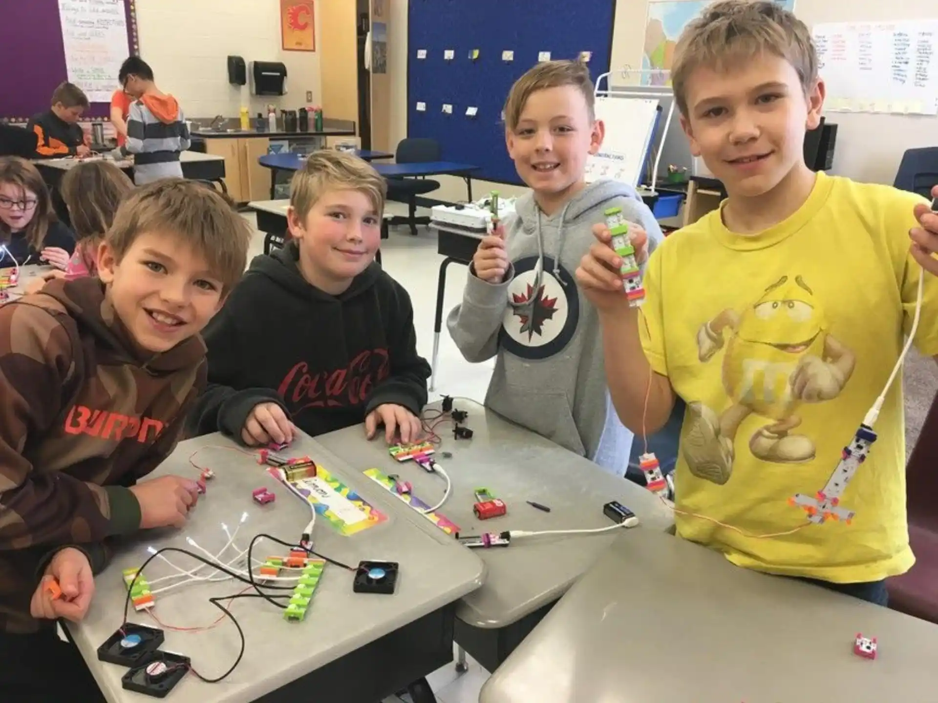 a group of children sitting at a table with a toy