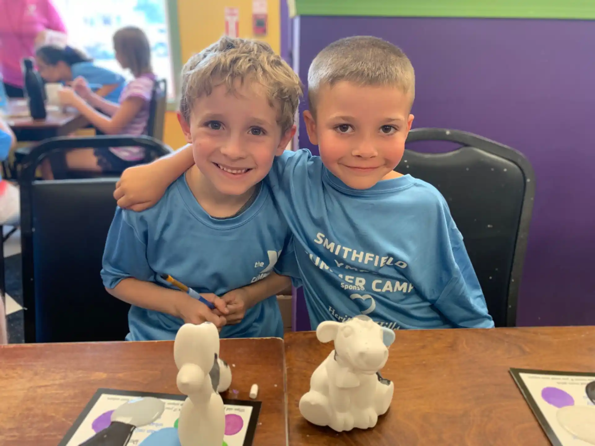 a couple of boys sitting at a table with a toy