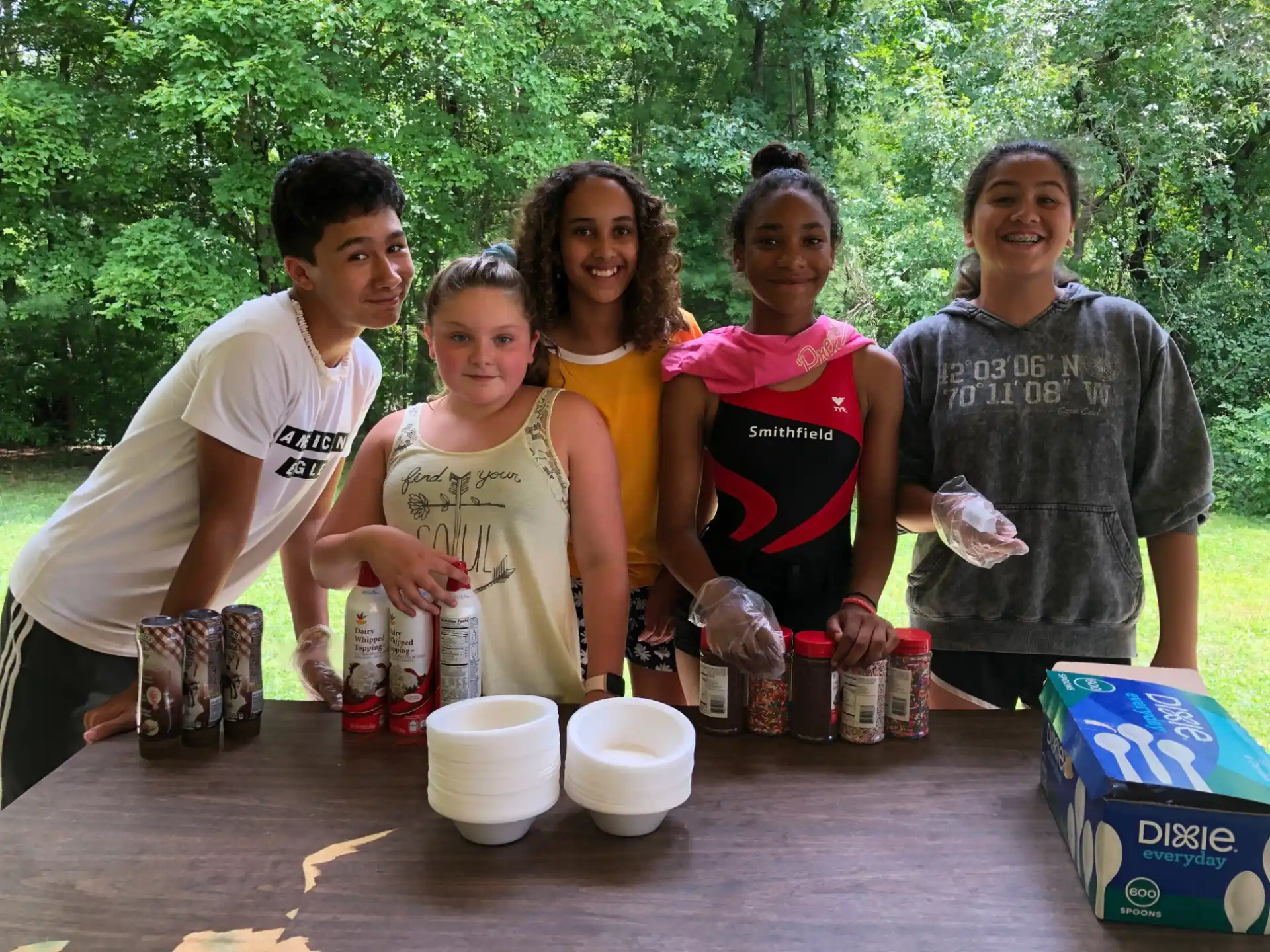 a group of people standing around a table with food and drinks