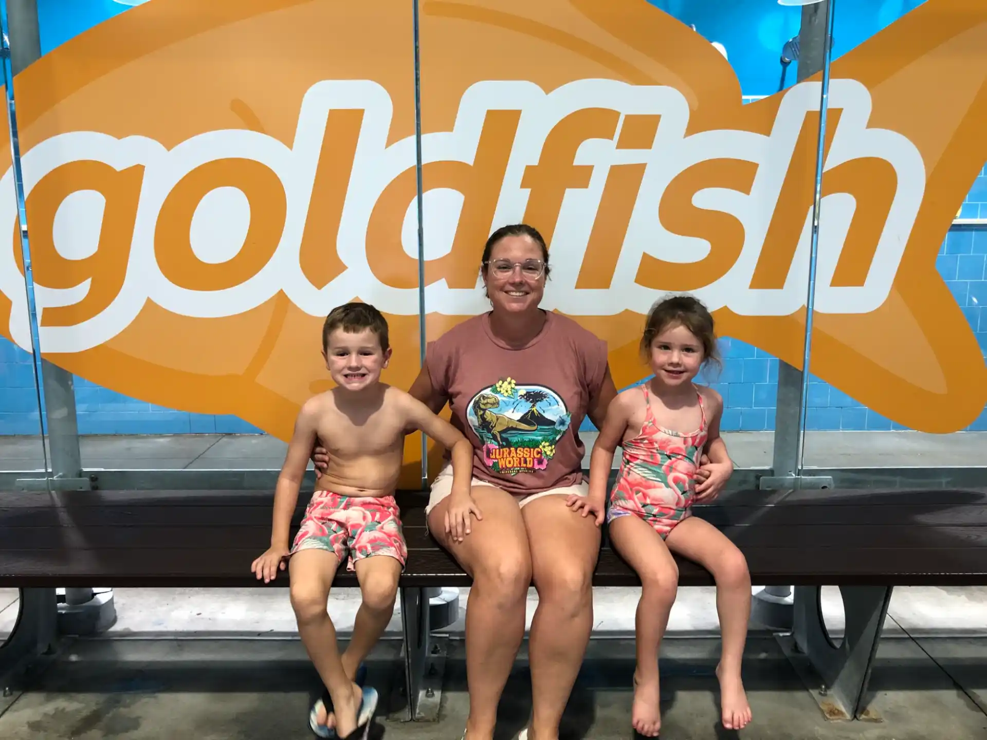 a person and two children sitting on a bench in front of a sign