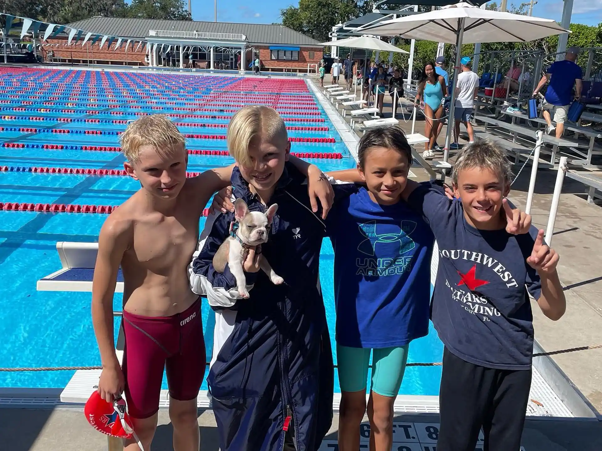 a group of children posing for a photo in front of a swimming pool