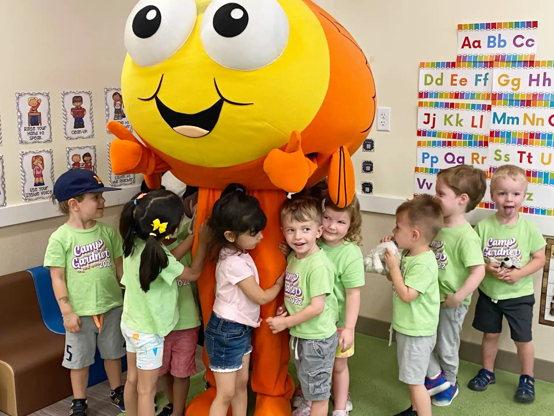 a group of children posing with a person in a yellow garment