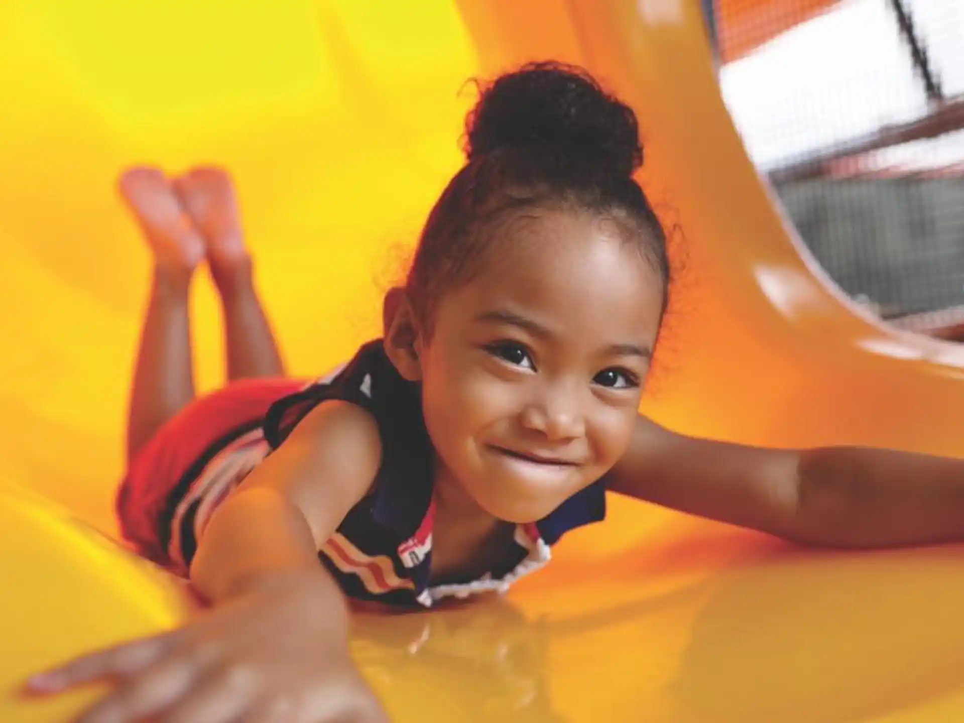 a child lying on a yellow slide