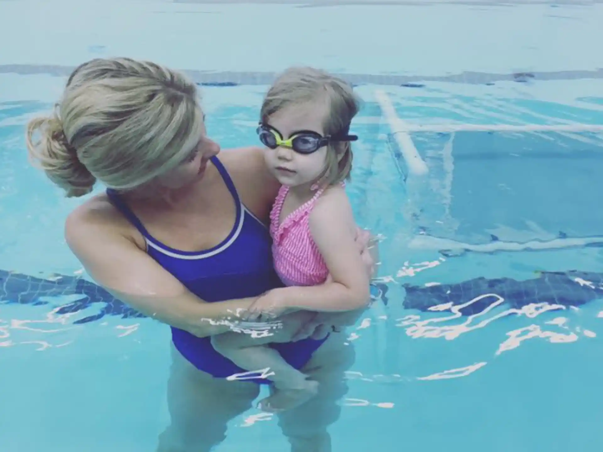 a woman holding a baby in a pool