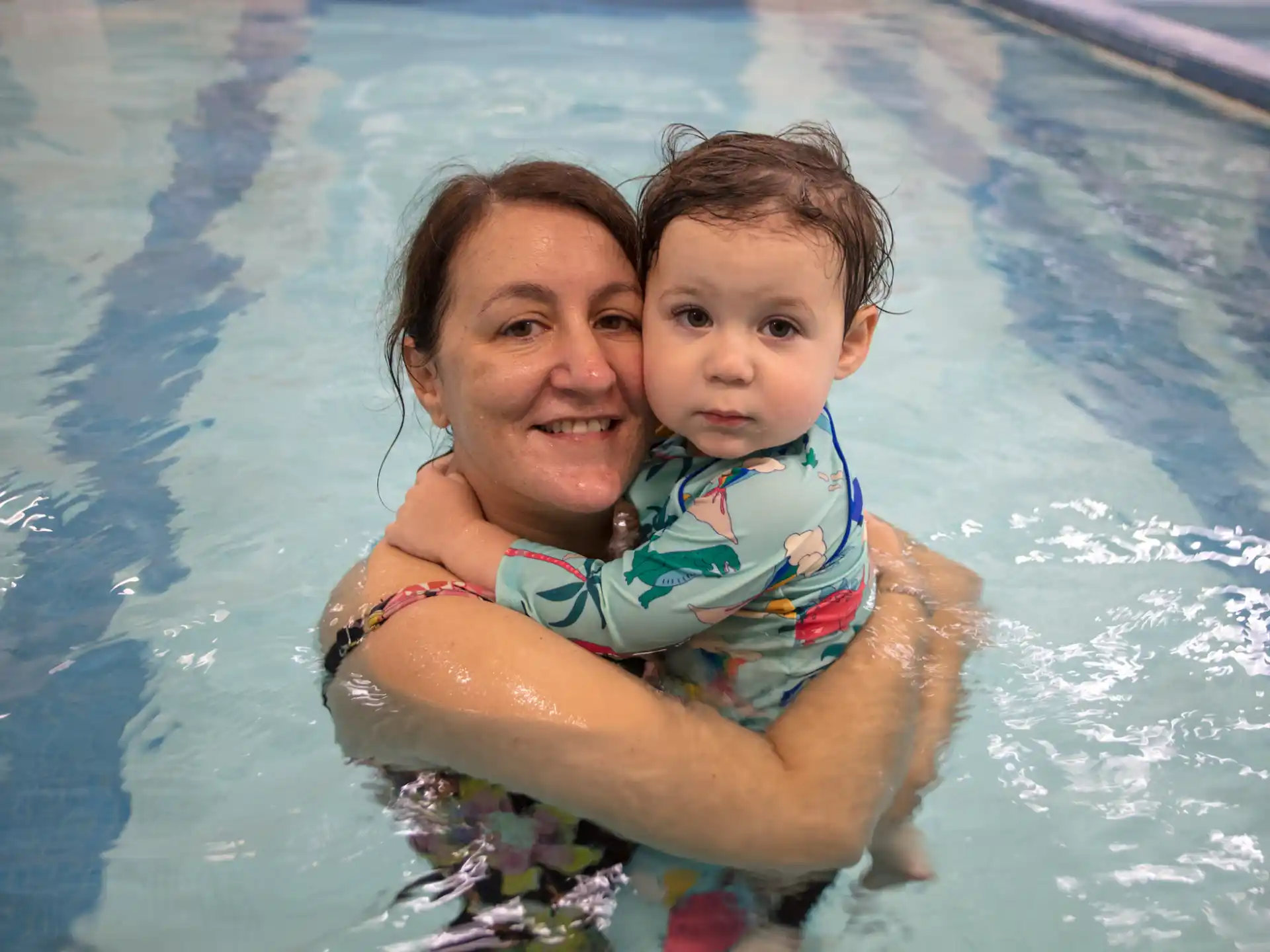 a person holding a baby in a pool