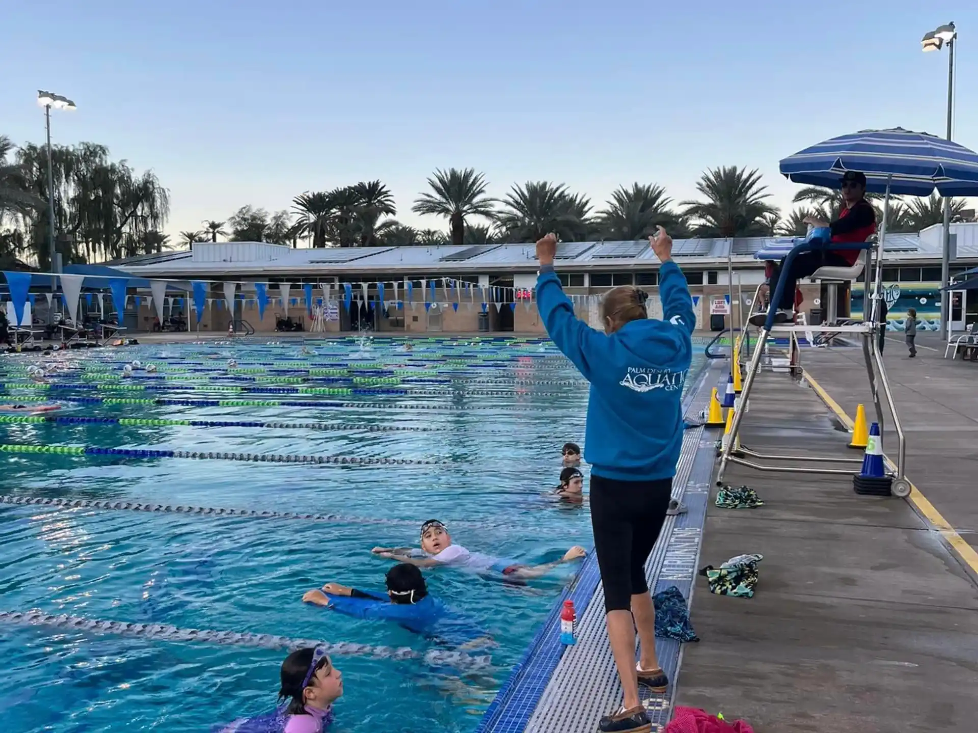 a person standing on a ledge above a pool with people in it