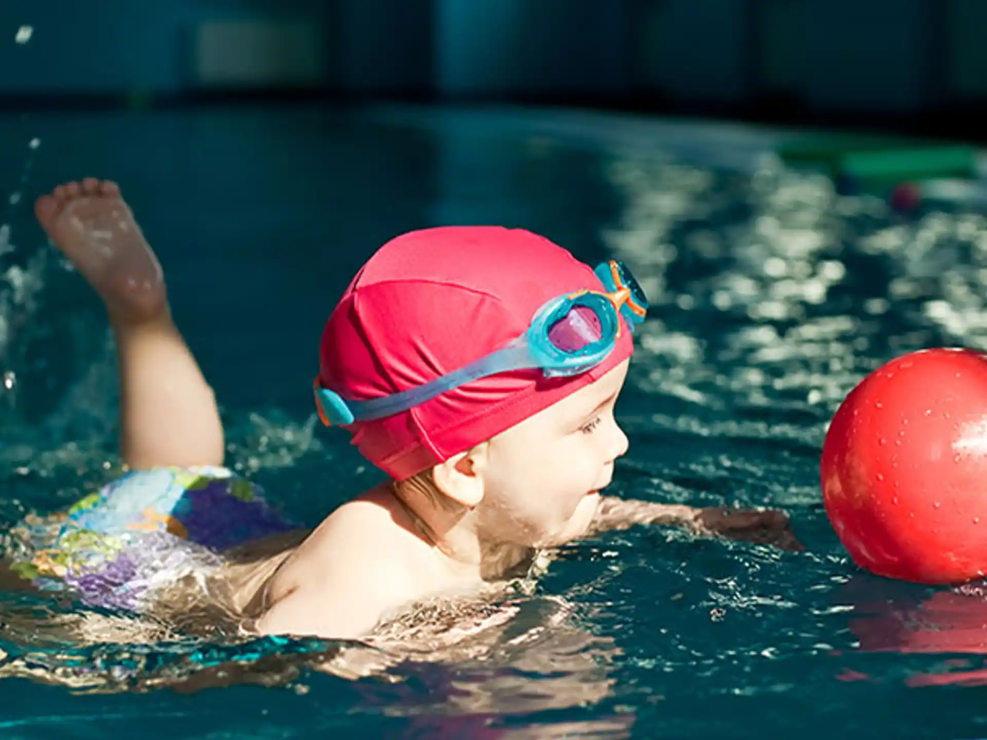 a child in a pool with a ball and a red ball