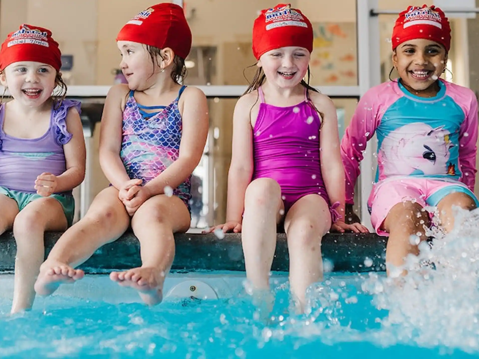 a group of girls in swimsuits sitting in a pool