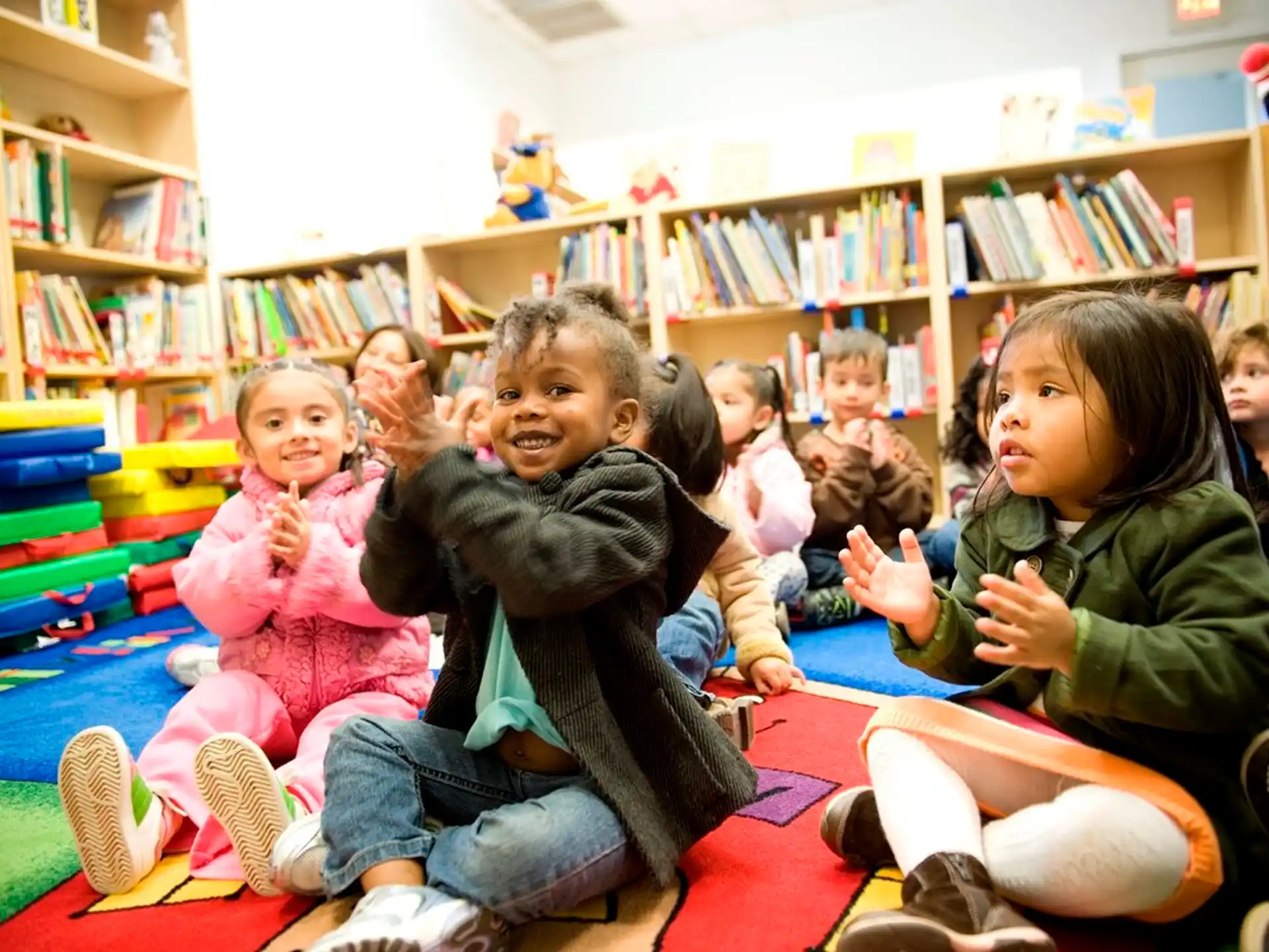 a group of children sitting on the floor in a library