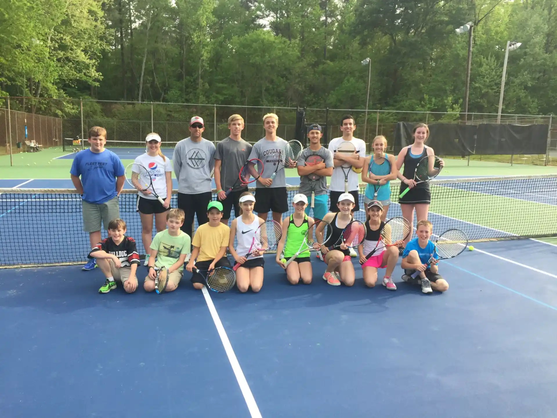 a group of people posing for a photo on a tennis court