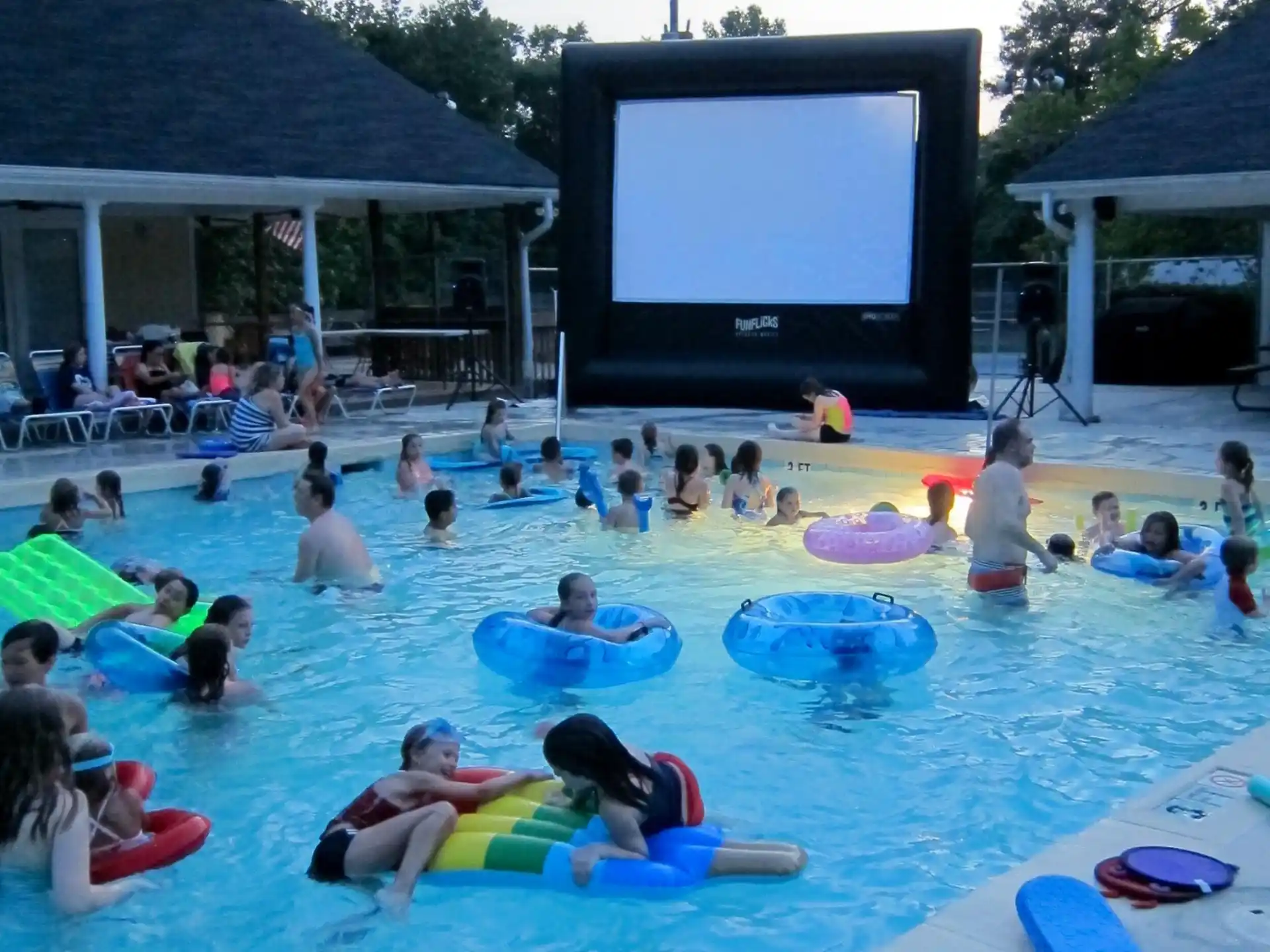 a large crowd of people in a pool watching a television