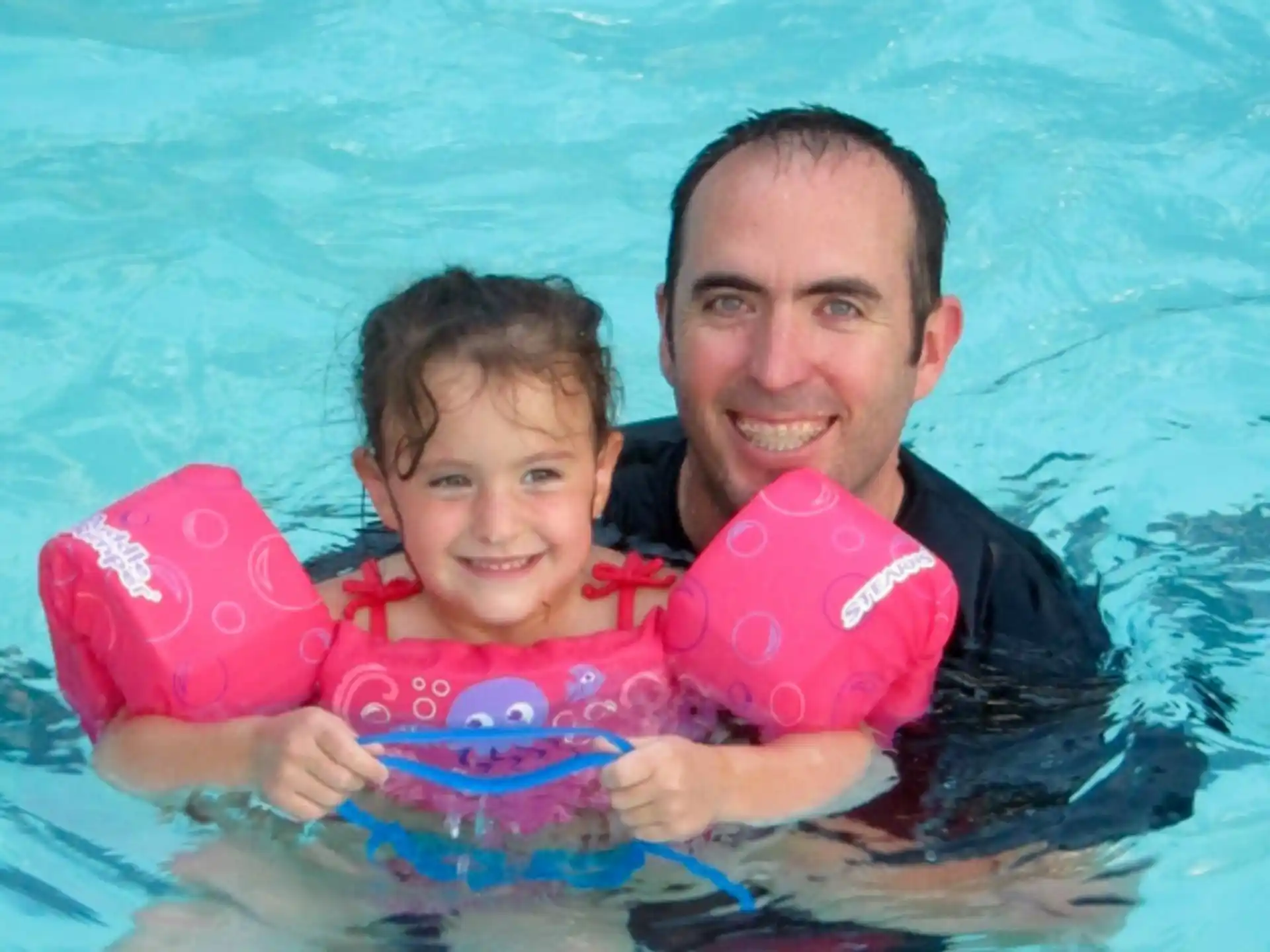 a person and a boy in a pool with a baby in a pool