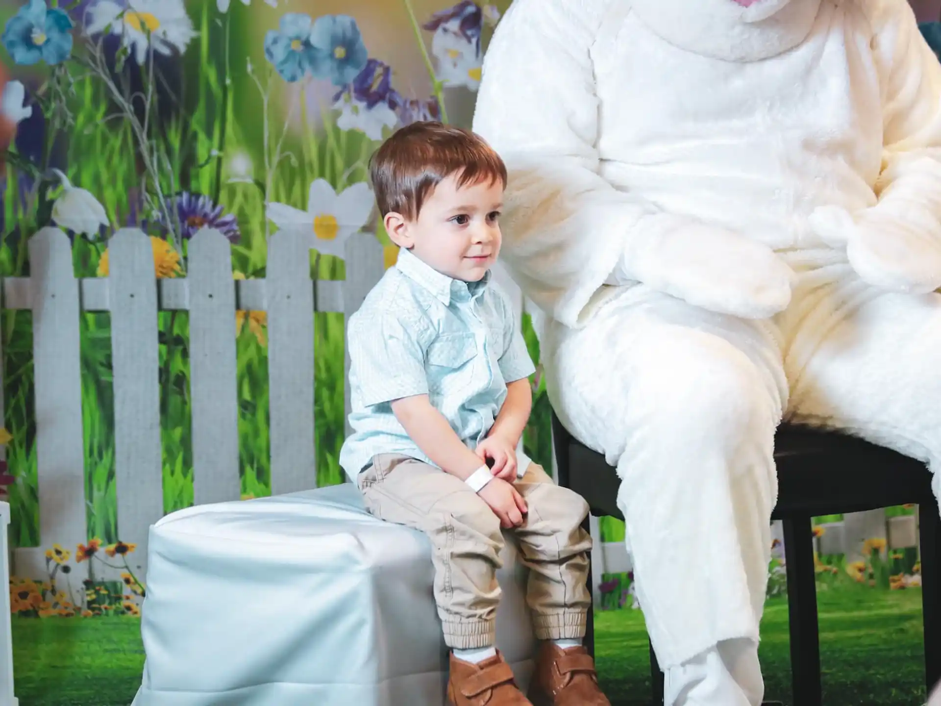 a boy sitting on a chair next to a person in a garment