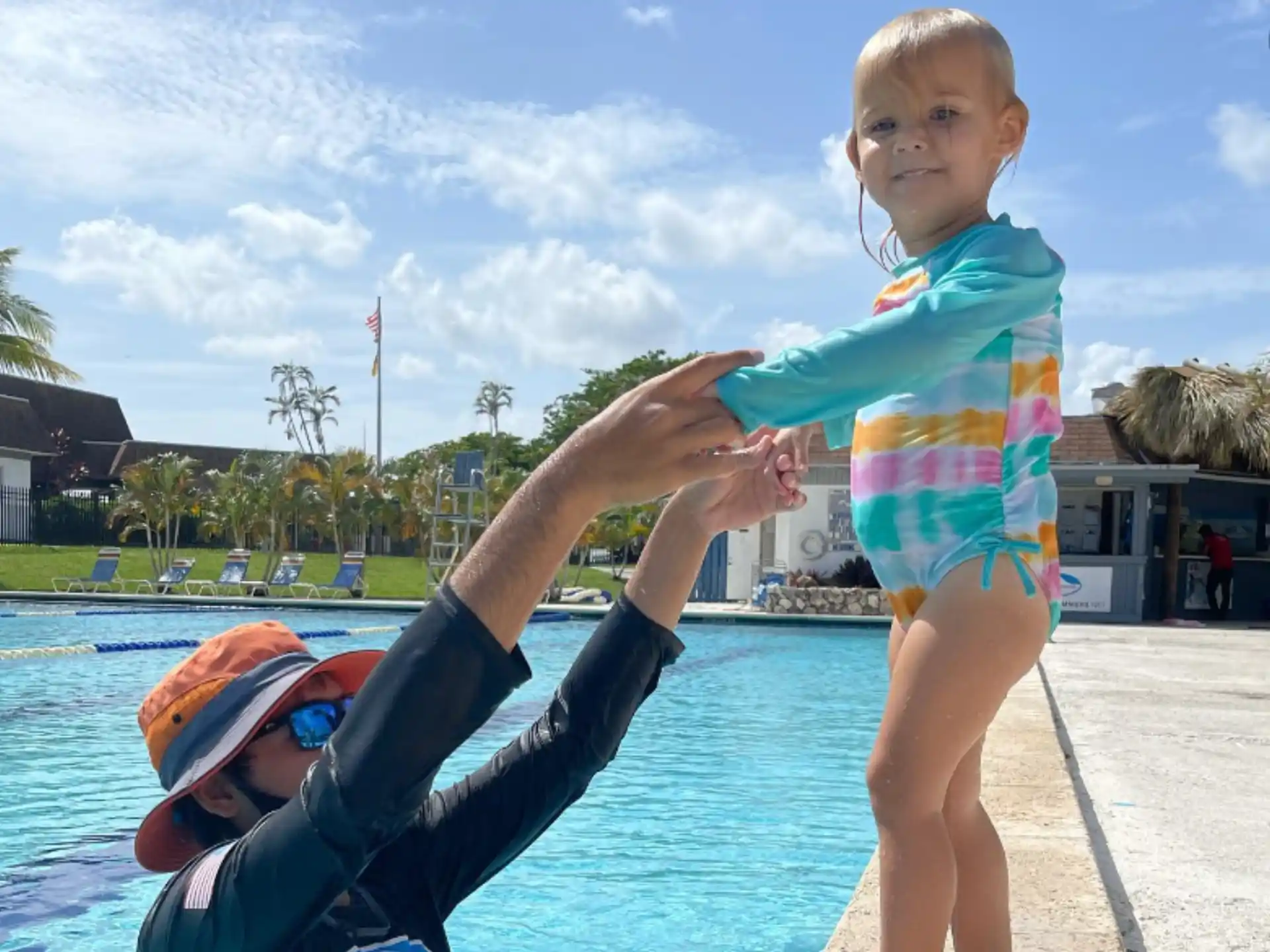 a baby on a man's hand by a pool