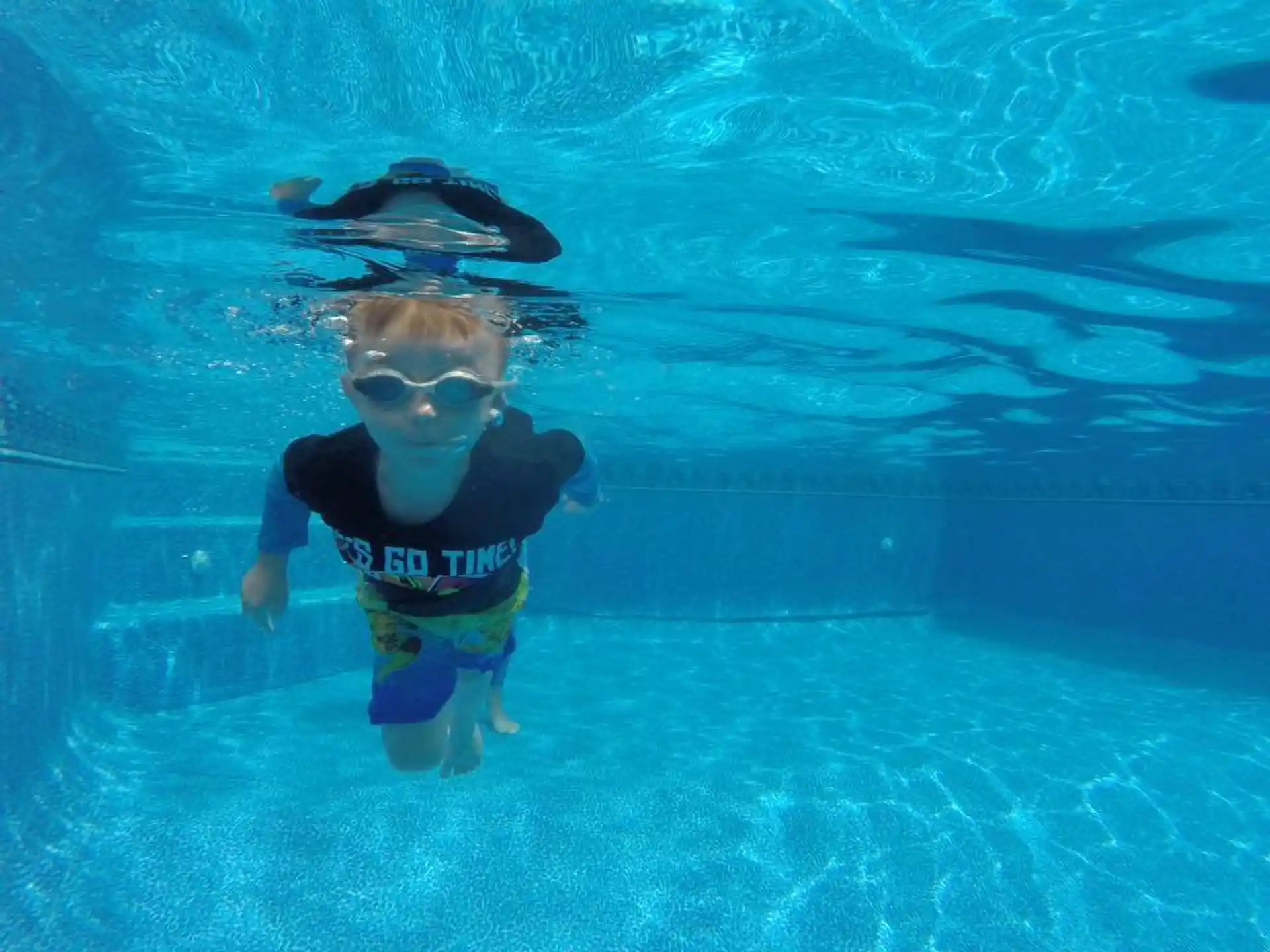 a boy in a pool with a fish on his head