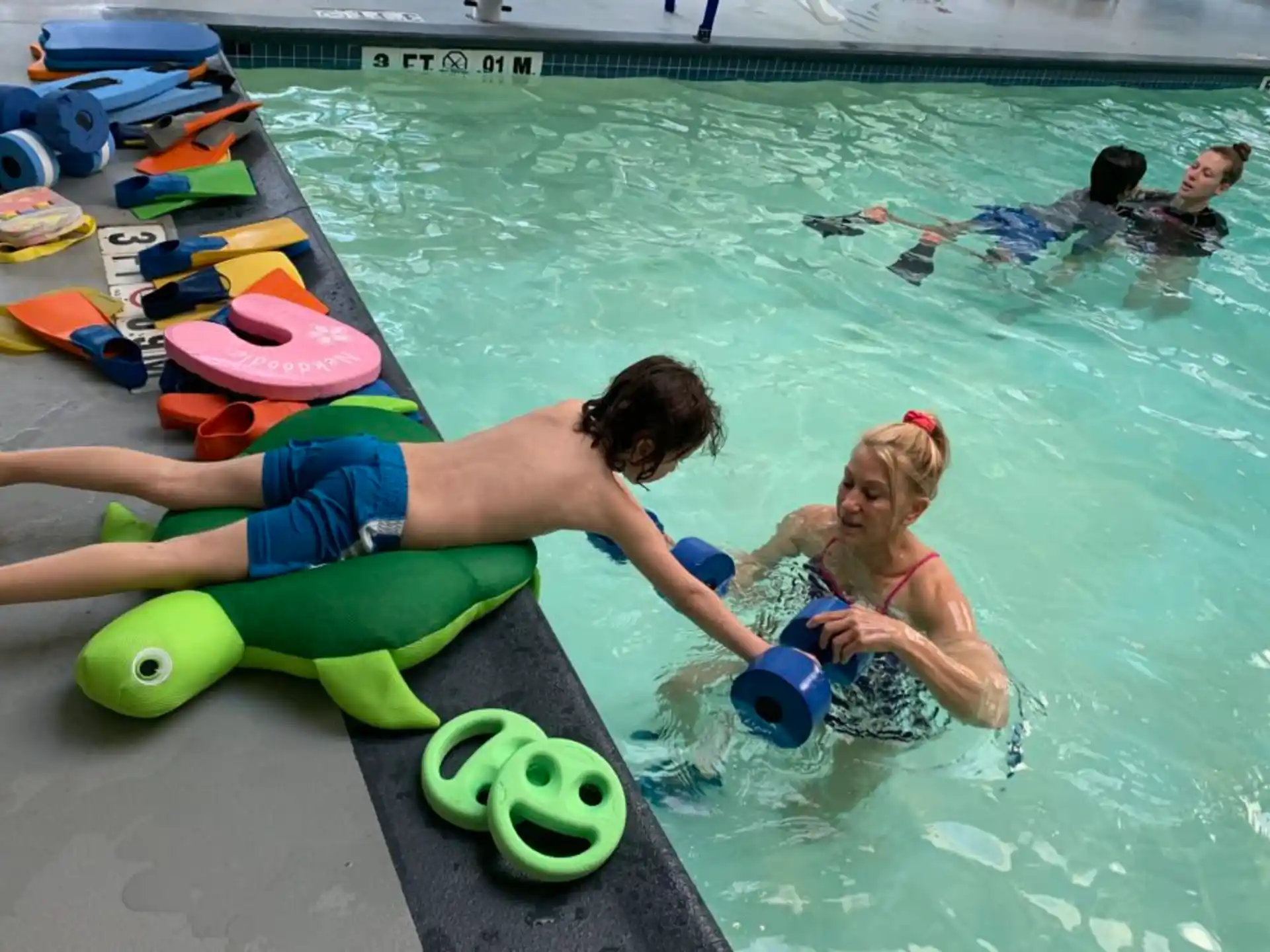 a man and a woman in a pool with a toy in it