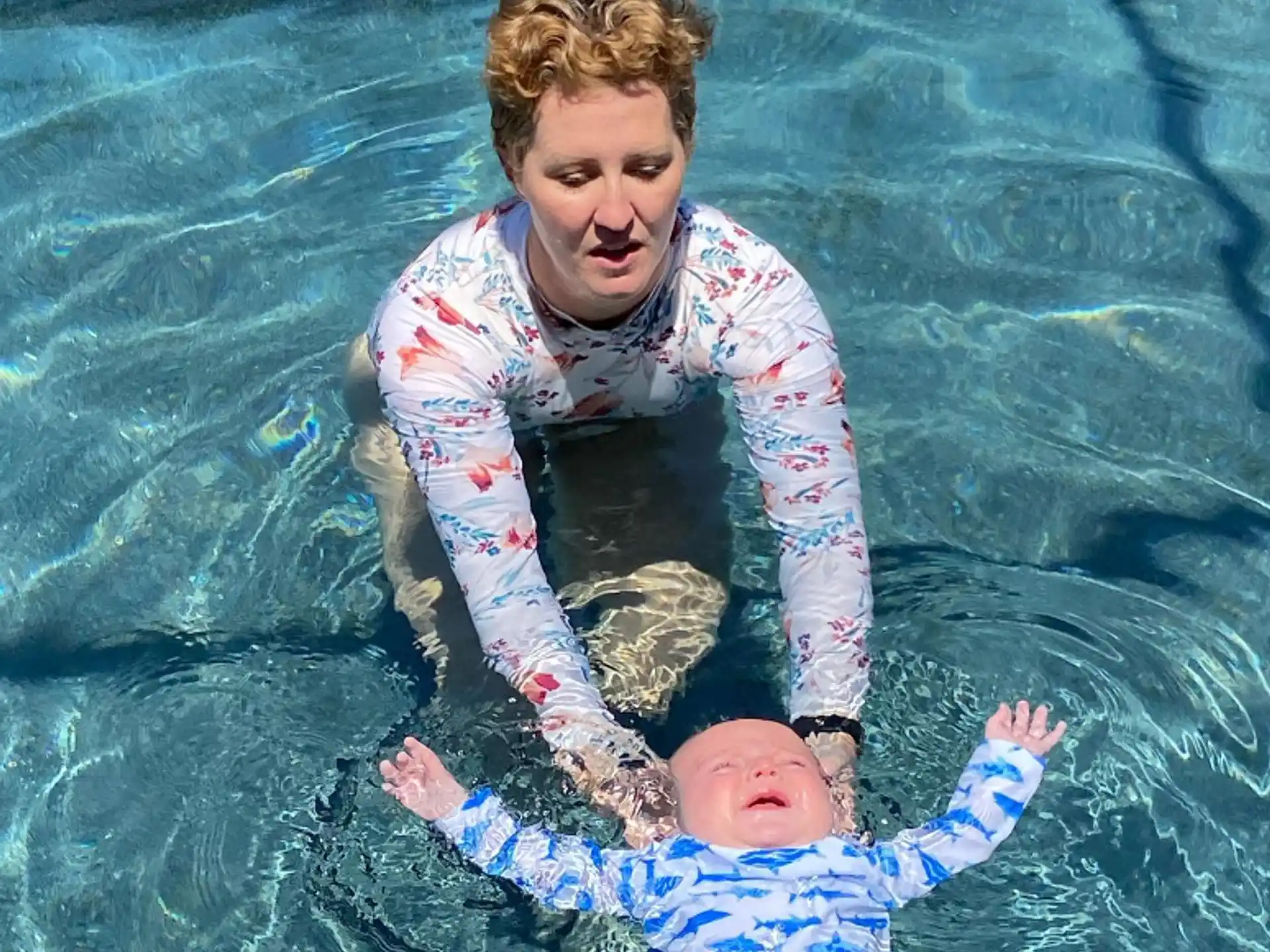 a person holding a baby in a pool