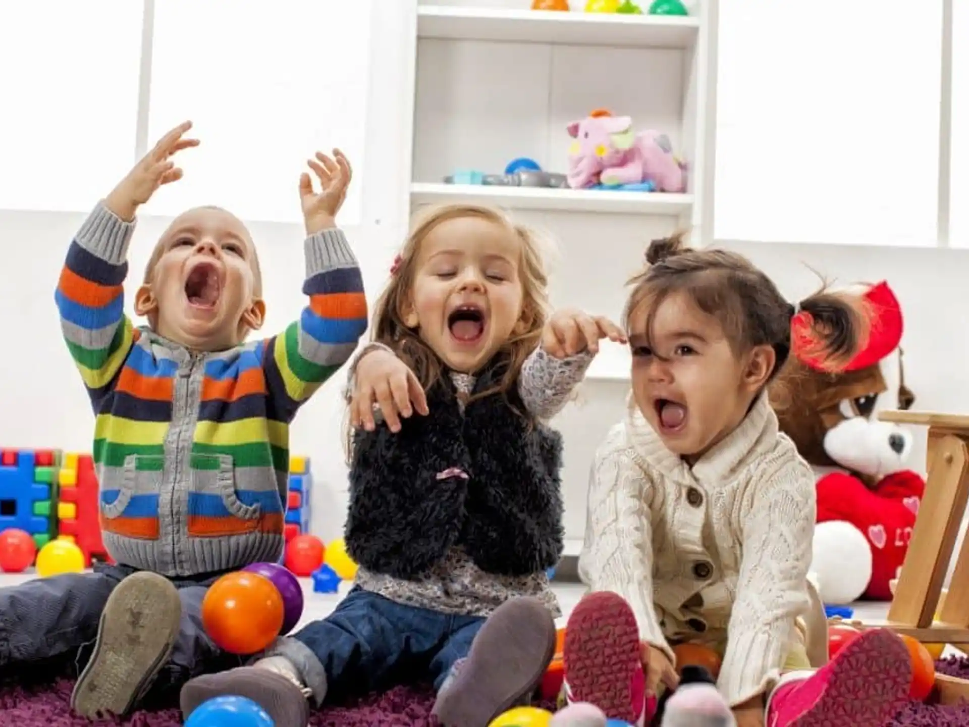 a group of children sitting on the floor with their arms up