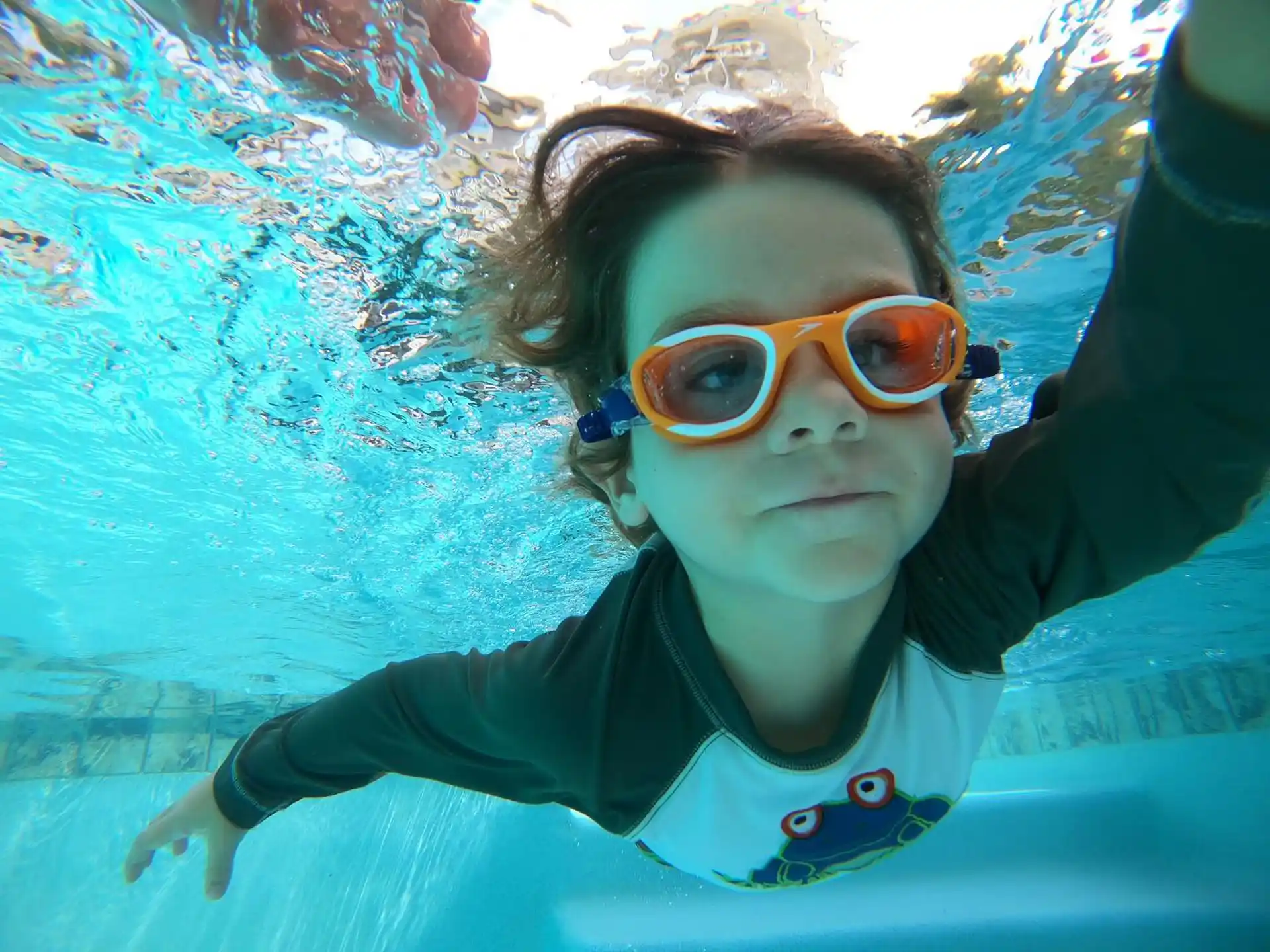 a woman wearing goggles and swimming underwater