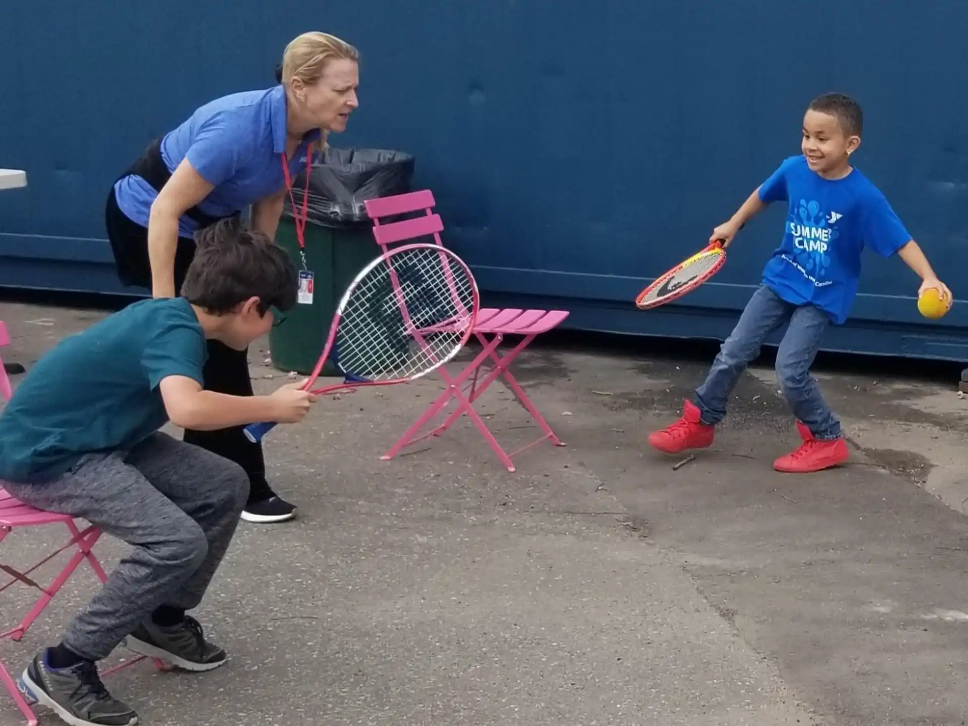 a person and kids playing with a ball and a racket