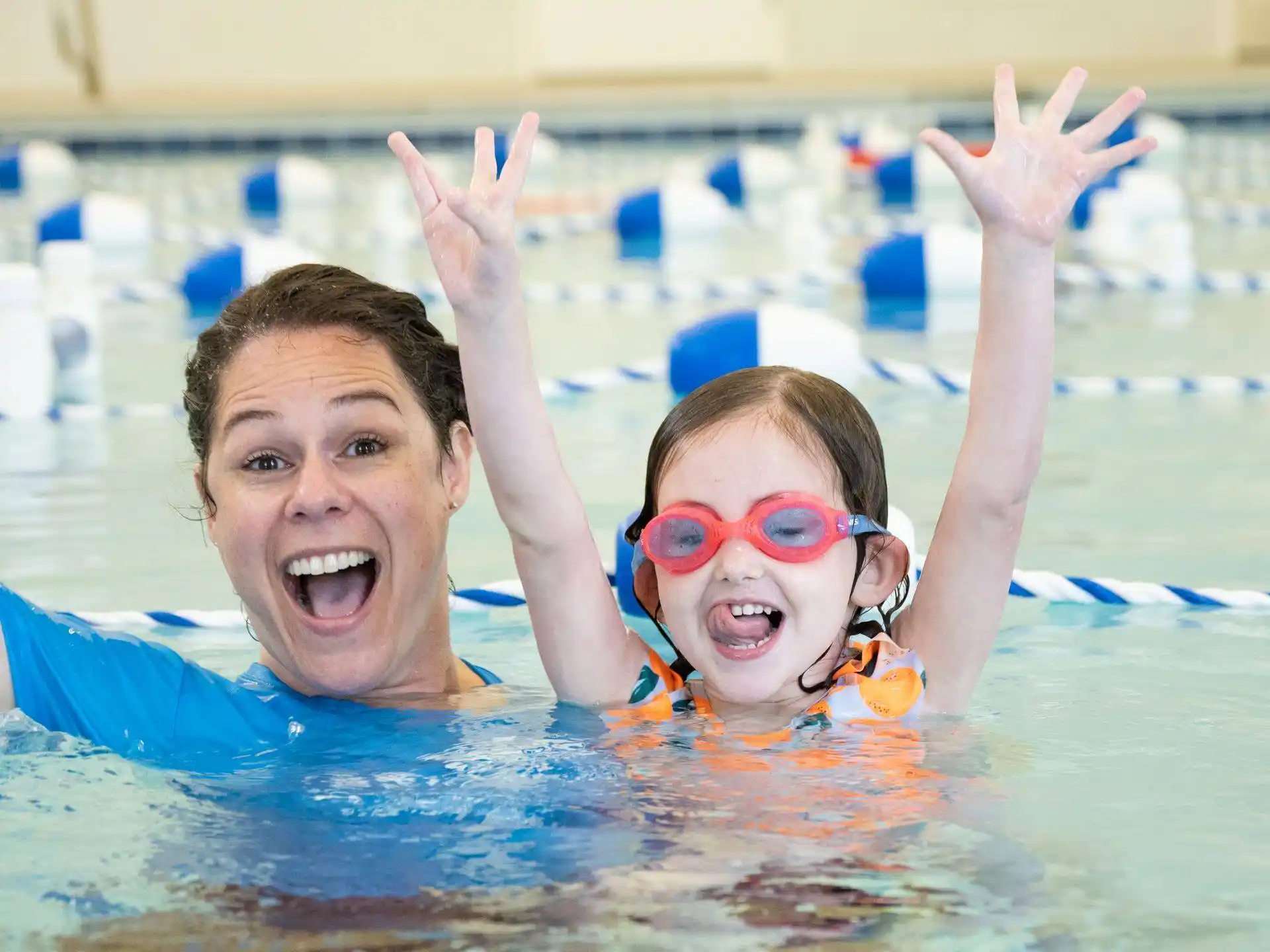 a man and a woman in a pool with their hands up
