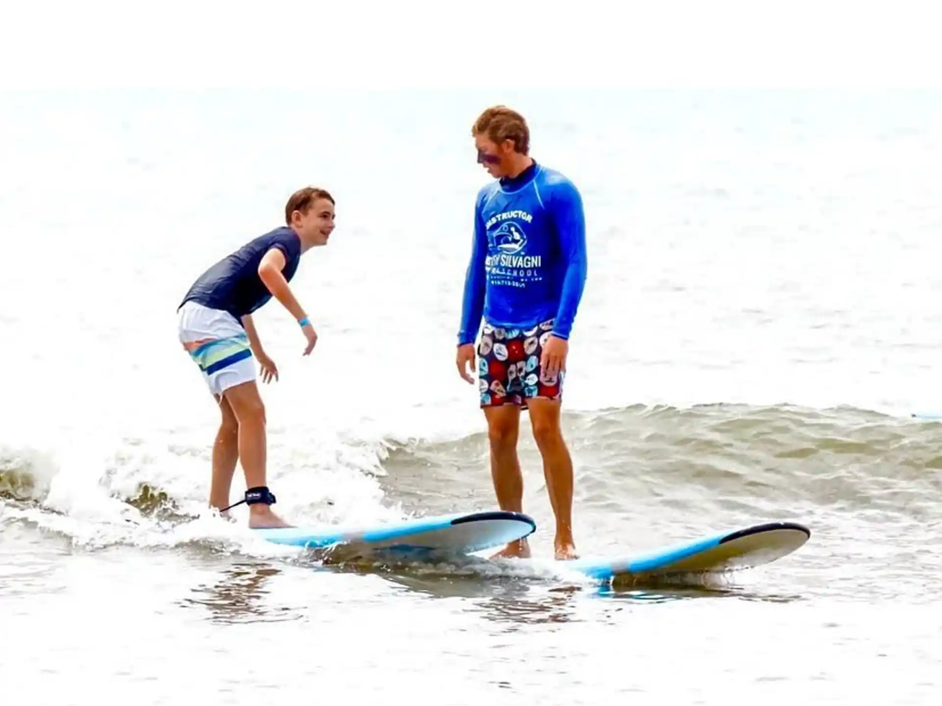 a couple of people stand on surfboards in the ocean