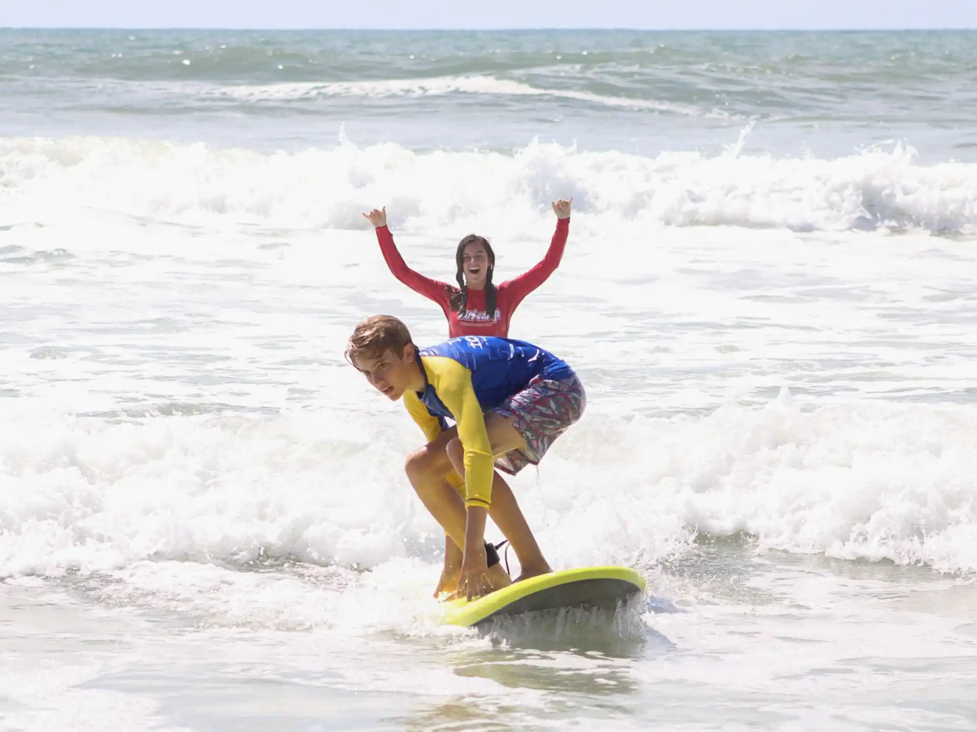 a person and a boy surfing in the sea