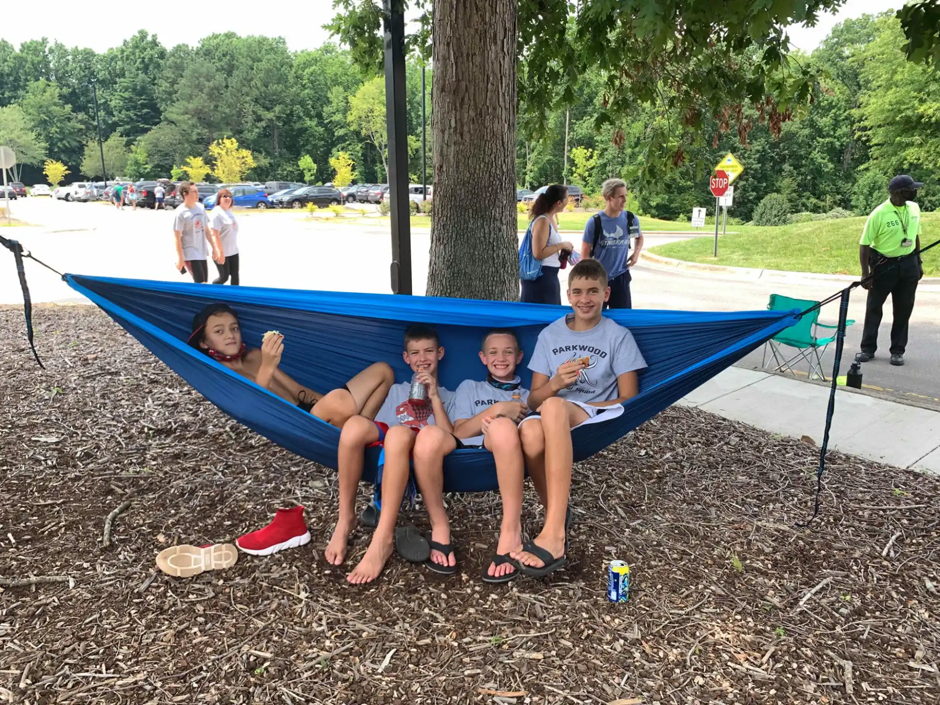 a group of people sitting on a blue trampoline by a tree