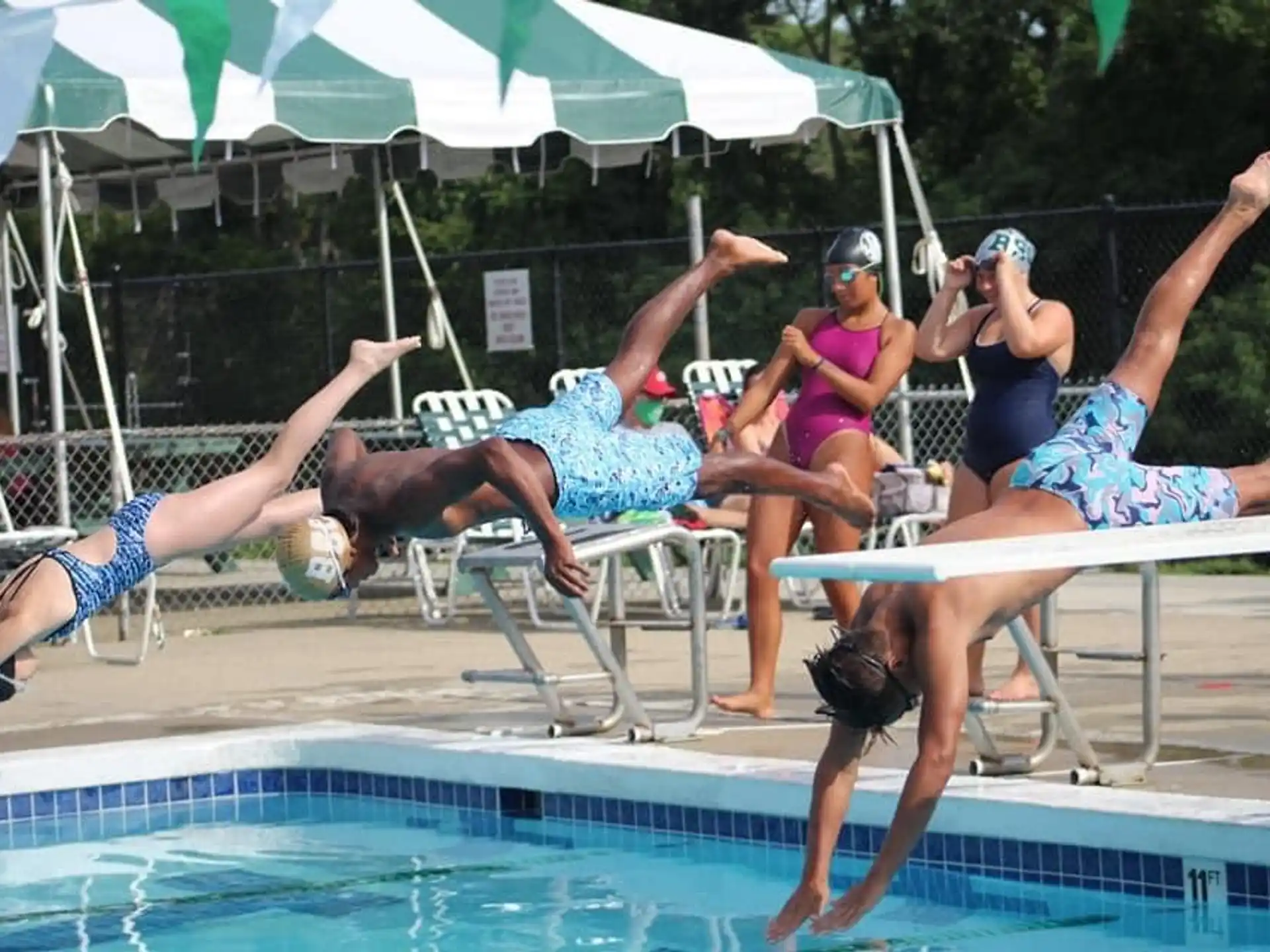 a group of people jumping into a pool