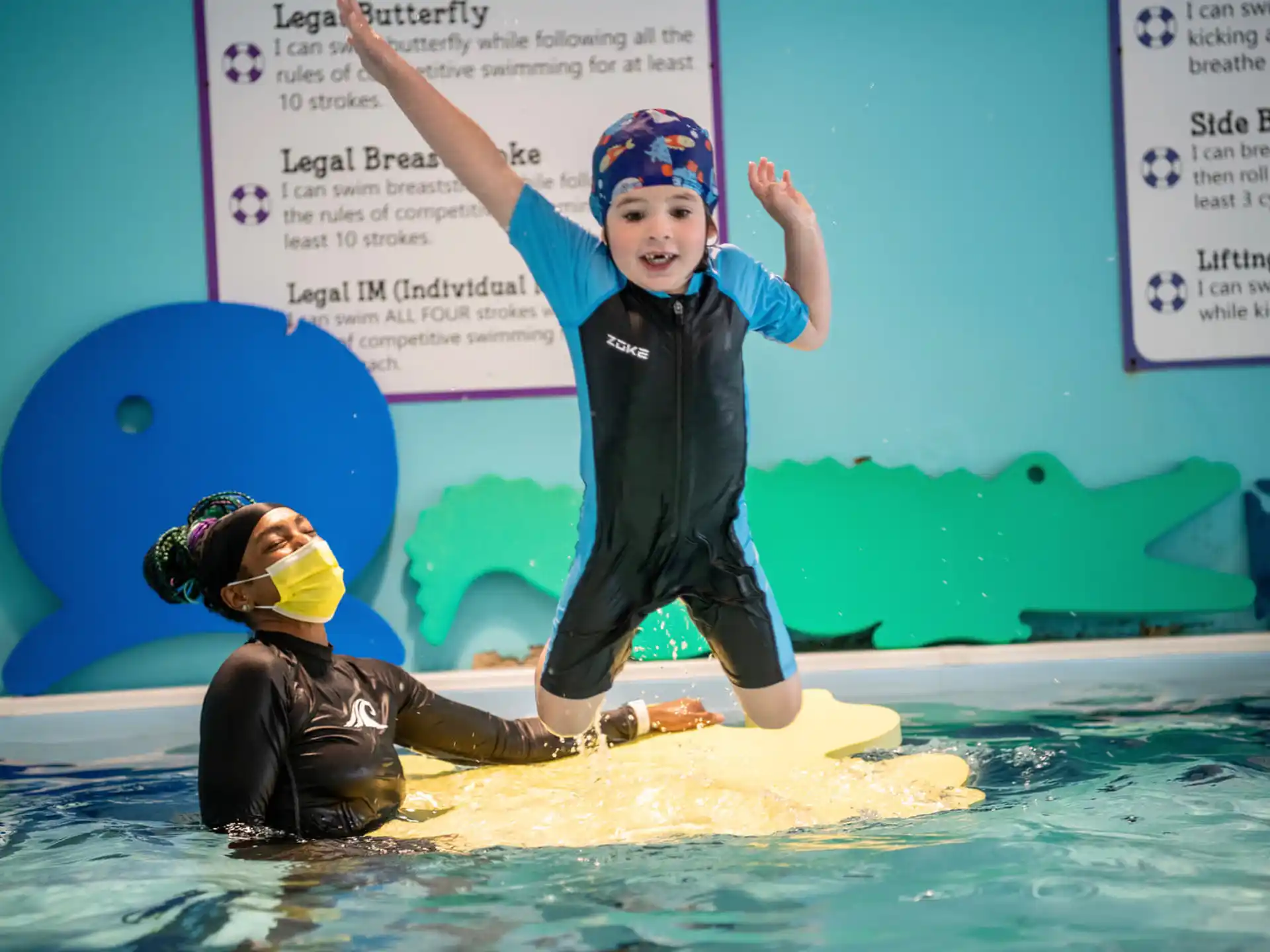 a couple of kids on a surfboard in a pool