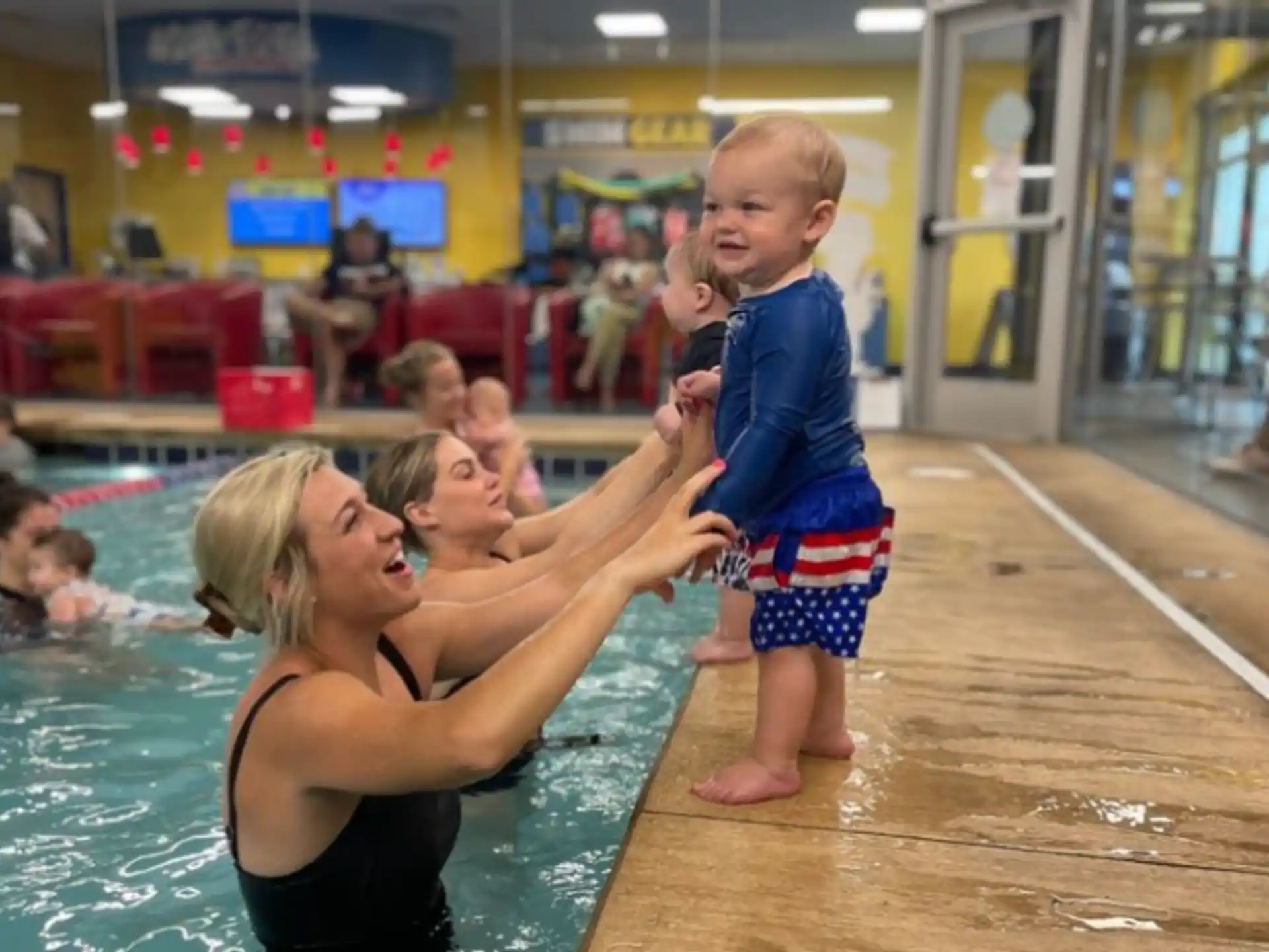 a person holding a baby in a pool