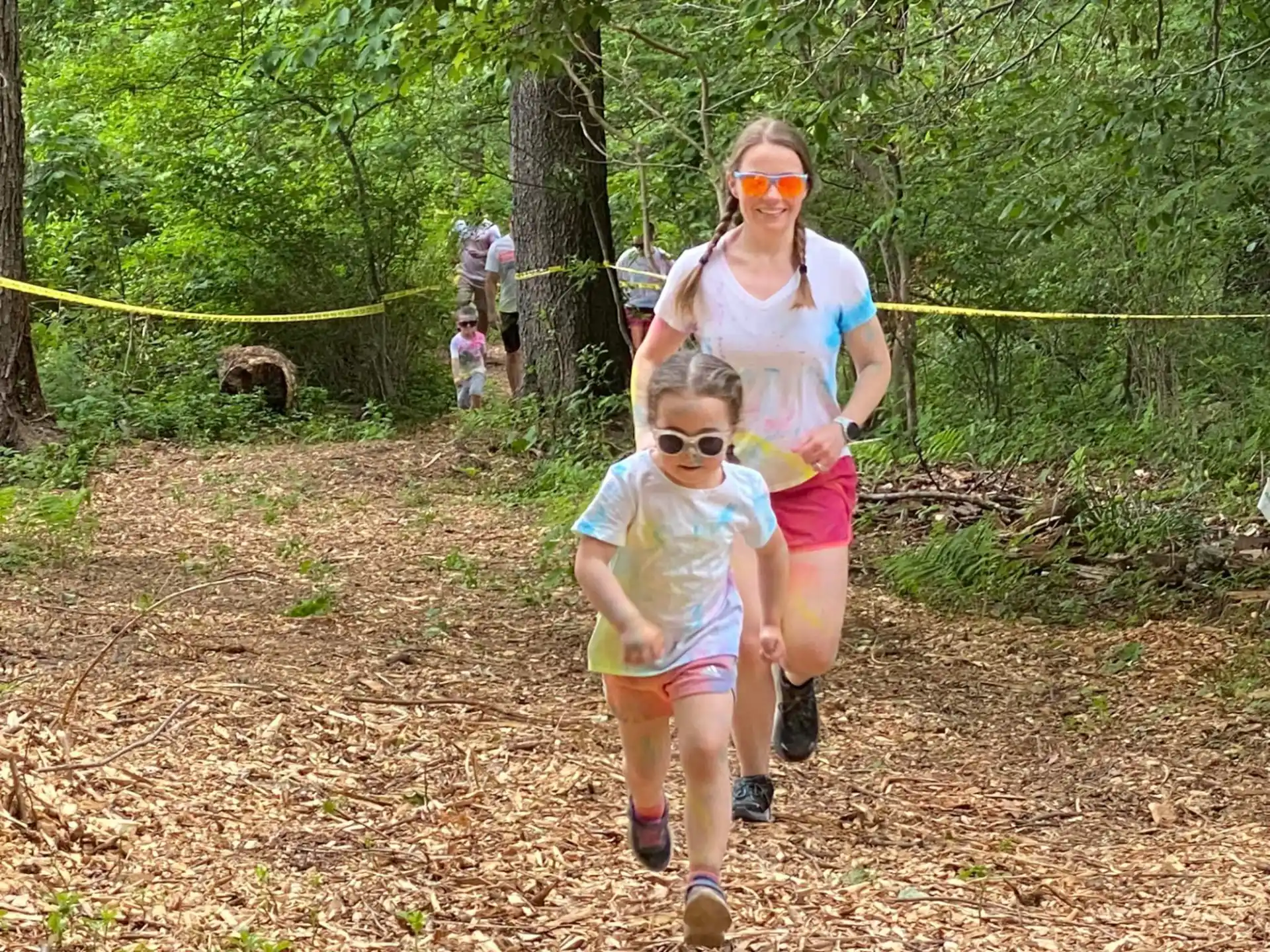a person and a child walking on a trail in the woods